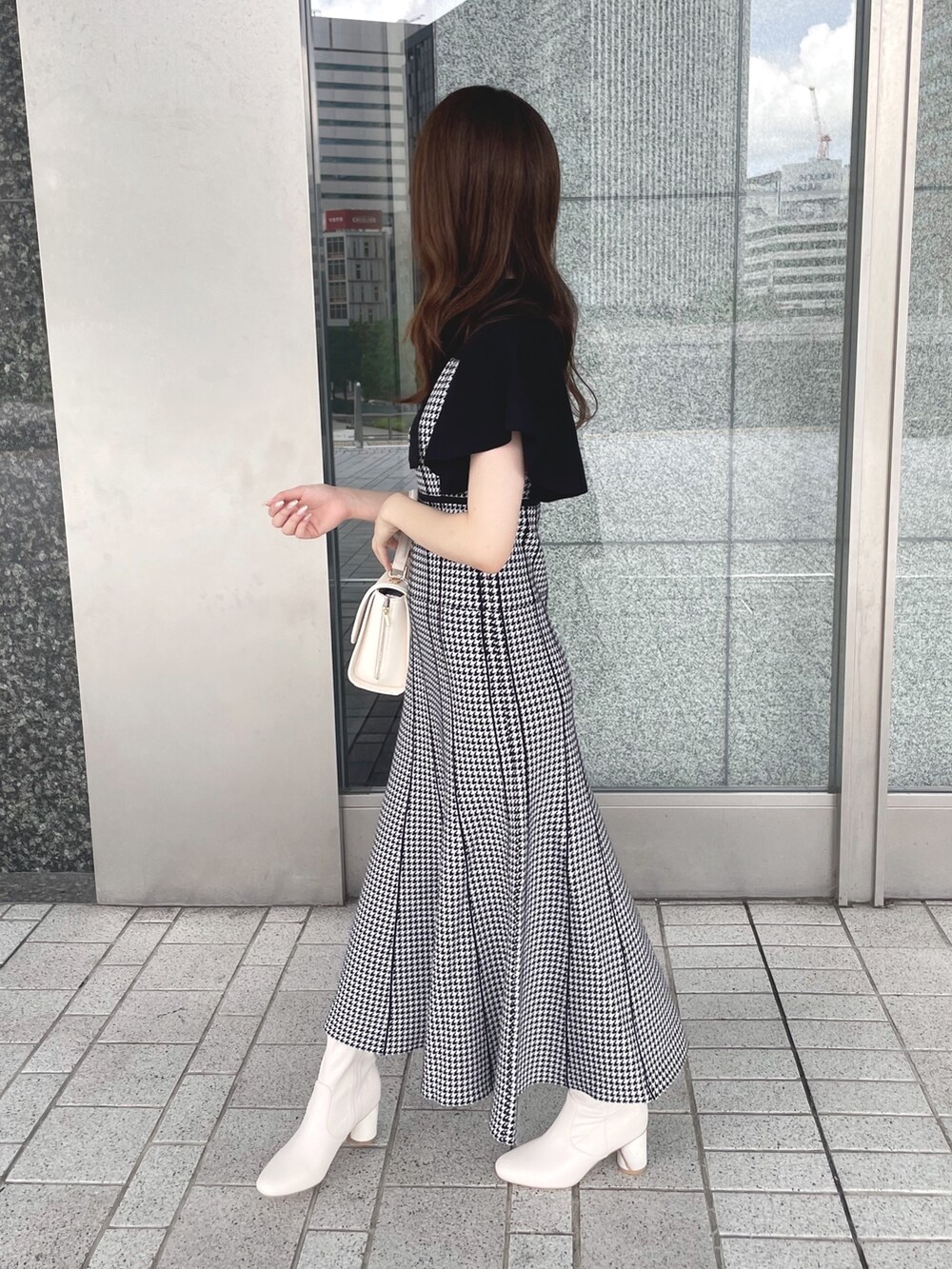 ブラック系のワンピース、ホワイト系のショルダーバッグ、ホワイト系のブーツを着用したレディースの夏コーディネートの4枚目の写真
