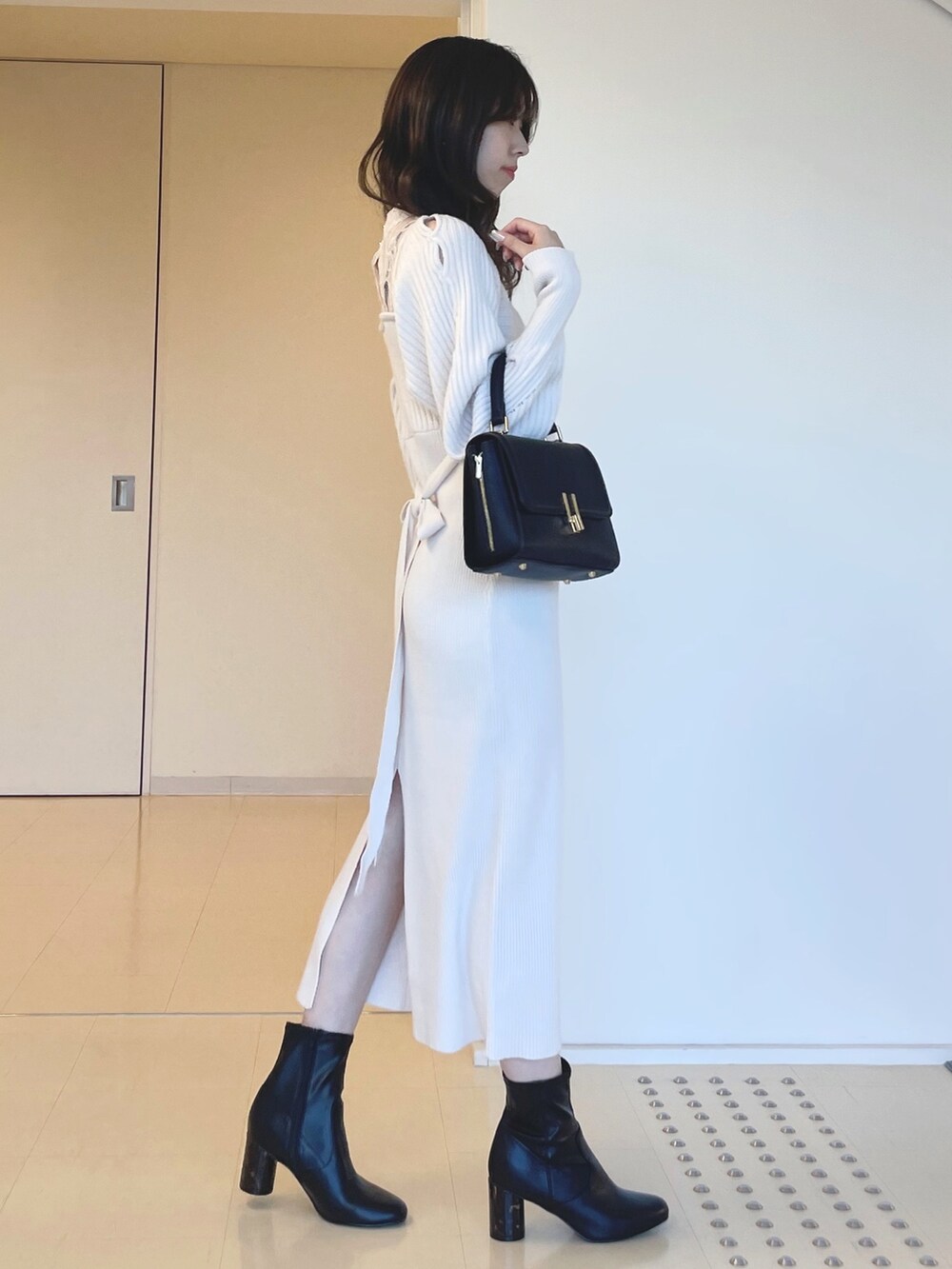 ホワイト系のワンピース、ブラック系のブーツ、ブラック系のショルダーバッグを着用したレディースの秋コーディネートの6枚目の写真