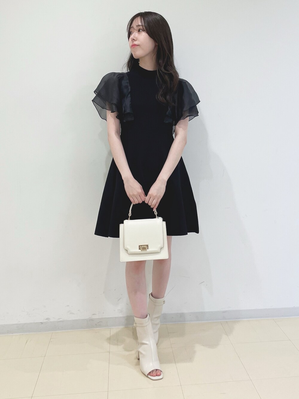 ブラック系のワンピース、ホワイト系のハンドバッグ、ホワイト系のブーツを着用したレディースの春コーディネートの3枚目の写真