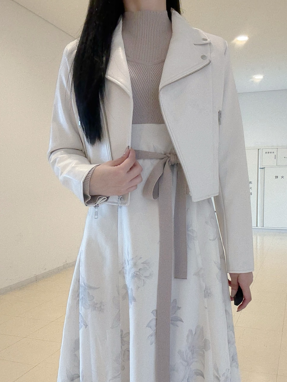 ホワイト系のライダースジャケット、ベージュ系のワンピース、ホワイト系のブーツを着用したレディースの秋コーディネートの6枚目の写真