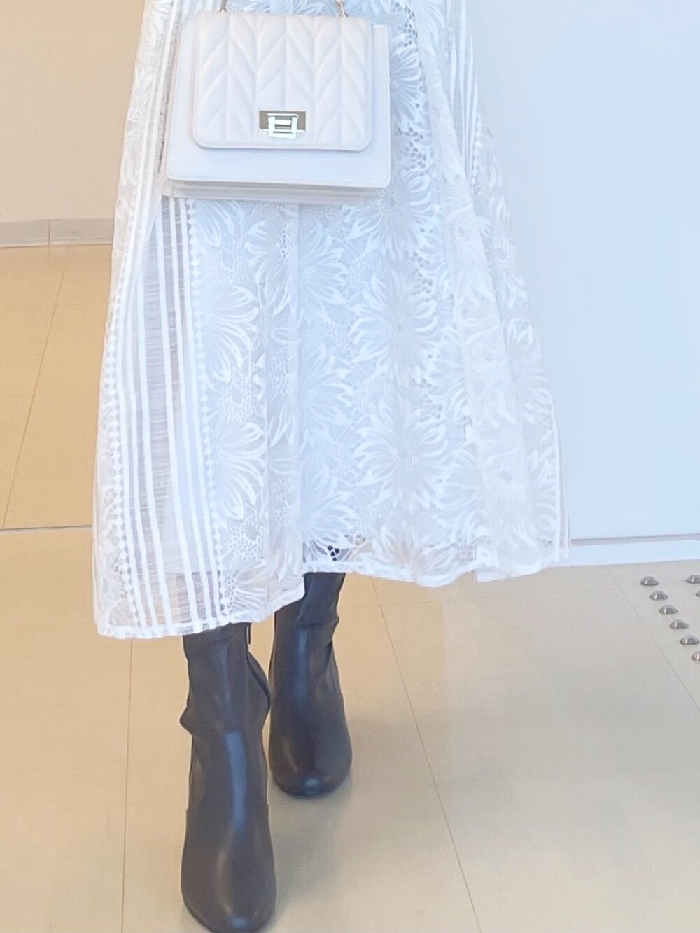 グレー系のニット/セーター、ホワイト系のスカート、ホワイト系のショルダーバッグを着用したレディースの秋コーディネートの5枚目の写真