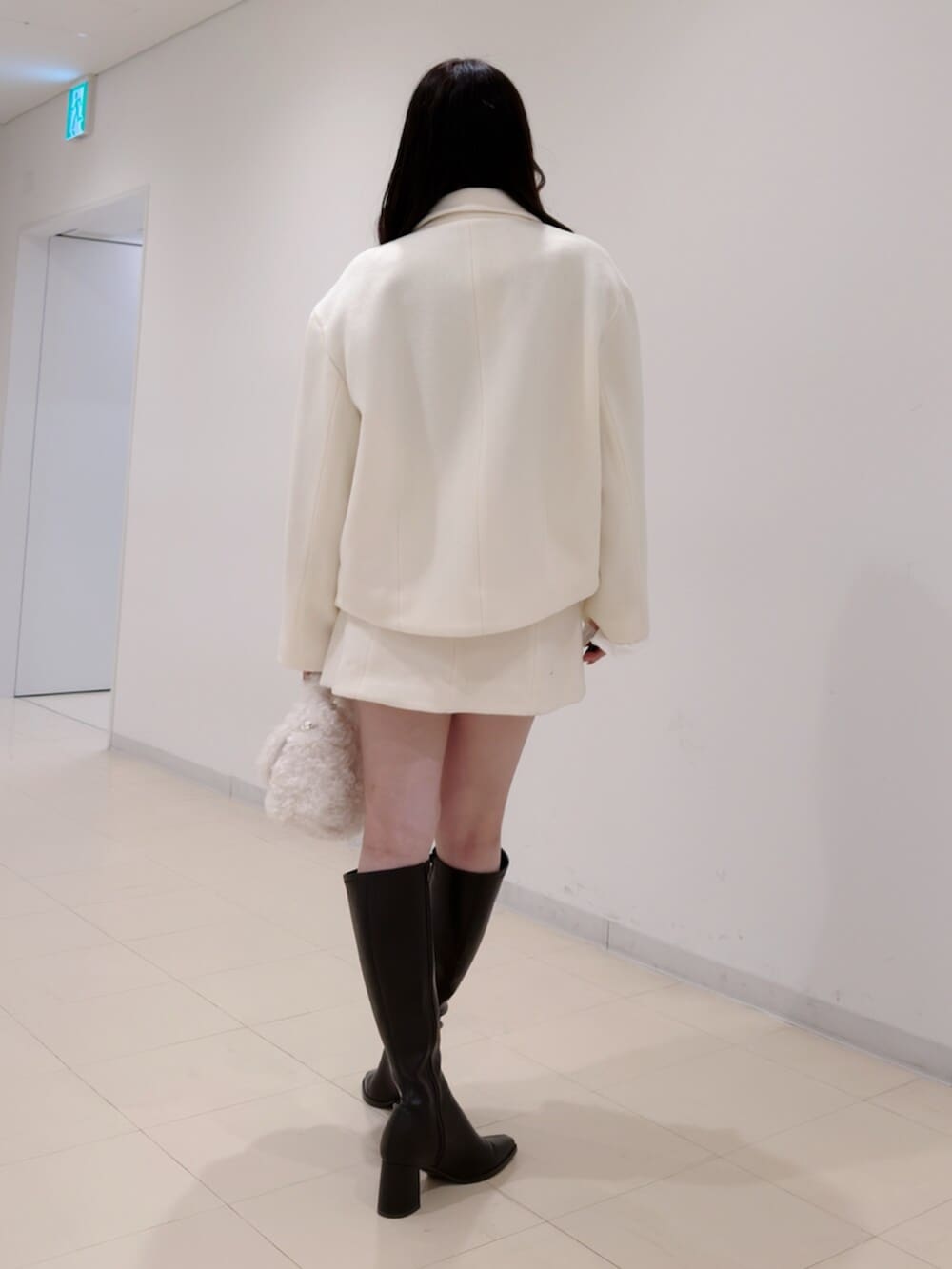 ホワイト系のハンドバッグ、ブラウン系のブーツ、ブラウン系のニット/セーターを着用したレディースの冬コーディネートの5枚目の写真