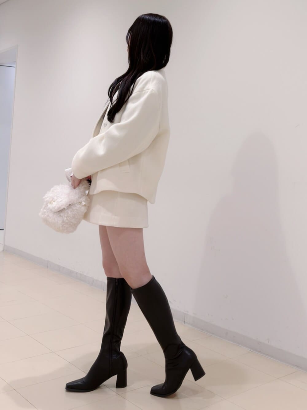 ホワイト系のハンドバッグ、ブラウン系のブーツ、ブラウン系のニット/セーターを着用したレディースの冬コーディネートの4枚目の写真