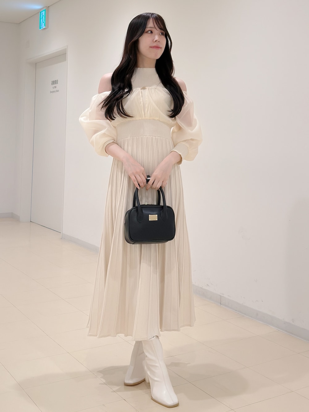 ホワイト系のワンピース、ブラック系のハンドバッグ、ホワイト系のブーツを着用したレディースの冬コーディネートの5枚目の写真