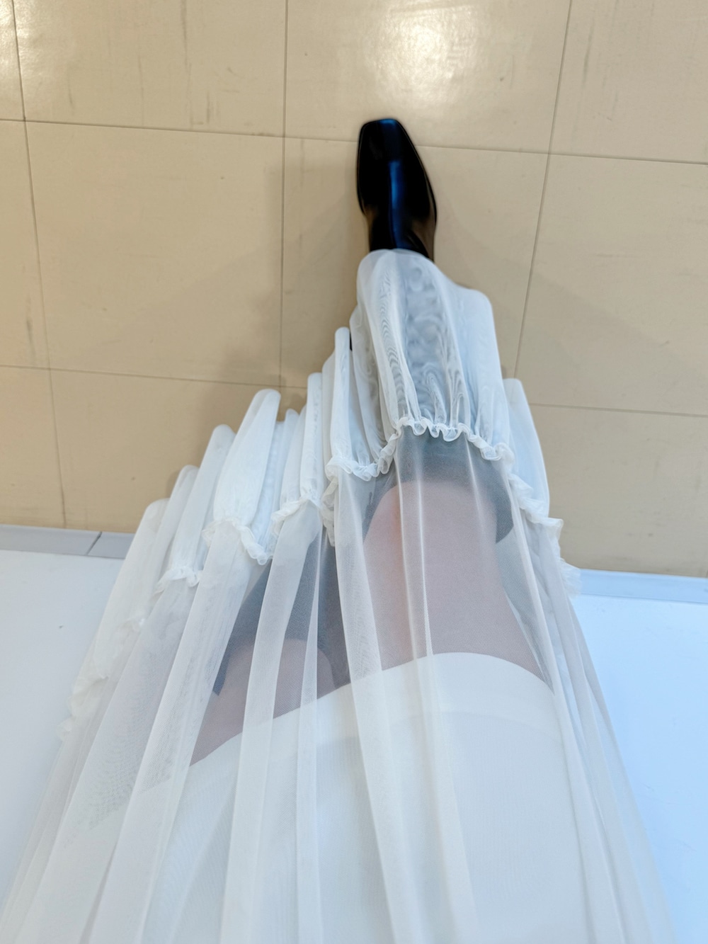 ブラック系のニット/セーター、ホワイト系のスカート、ブラック系のハンドバッグを着用したレディースの夏コーディネートの6枚目の写真