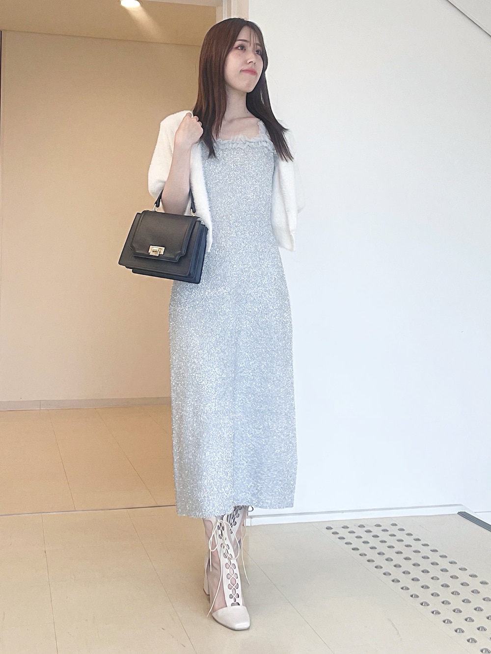 ホワイト系のカーディガン/ボレロ、シルバー系のワンピース、ブラック系のハンドバッグを着用したレディースの秋コーディネートの3枚目の写真