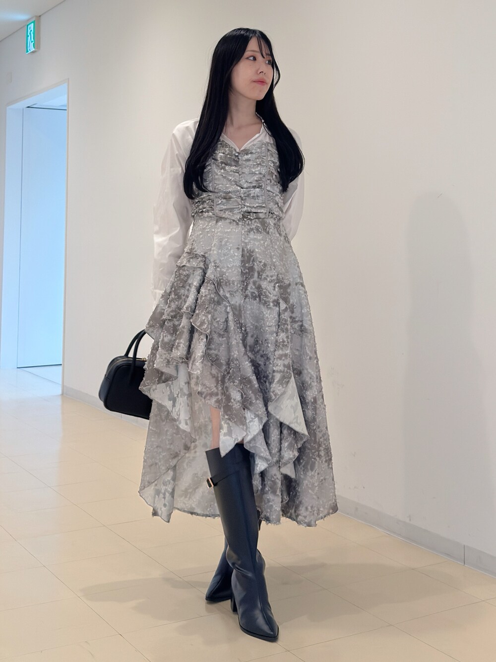 グリーン系のワンピース、ブラック系のハンドバッグ、ブラック系のブーツを着用したレディースの秋コーディネートの3枚目の写真