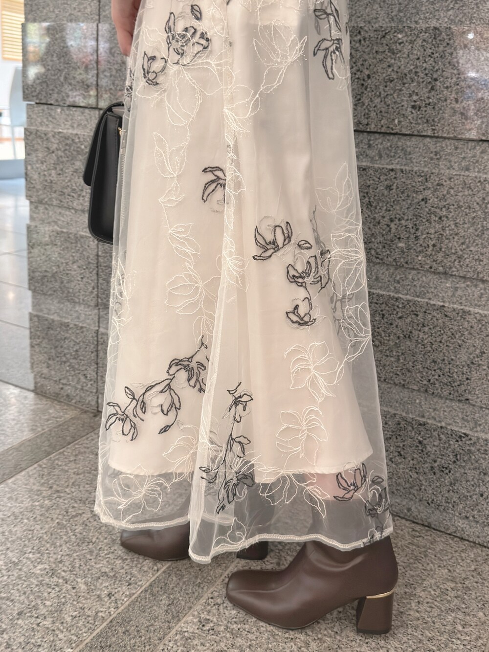 ホワイト系のカーディガン/ボレロ、ホワイト系のスカート、ブラック系のハンドバッグを着用したレディースの秋コーディネートの6枚目の写真