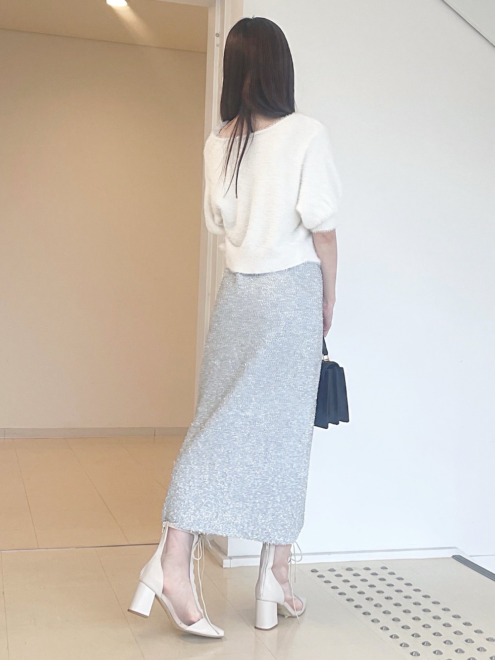 ホワイト系のカーディガン/ボレロ、シルバー系のワンピース、ブラック系のハンドバッグを着用したレディースの秋コーディネートの4枚目の写真