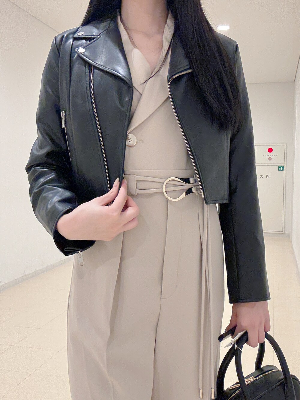 ブラック系のライダースジャケット、ベージュ系のつなぎ/オールインワン、ブラック系のハンドバッグを着用したレディースの秋コーディネートの5枚目の写真