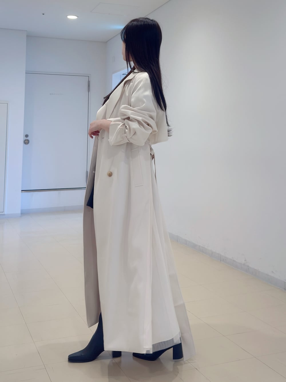 ホワイト系のトレンチコート、その他のニット/セーター、グレー系のスカートを着用したレディースの冬コーディネートの3枚目の写真