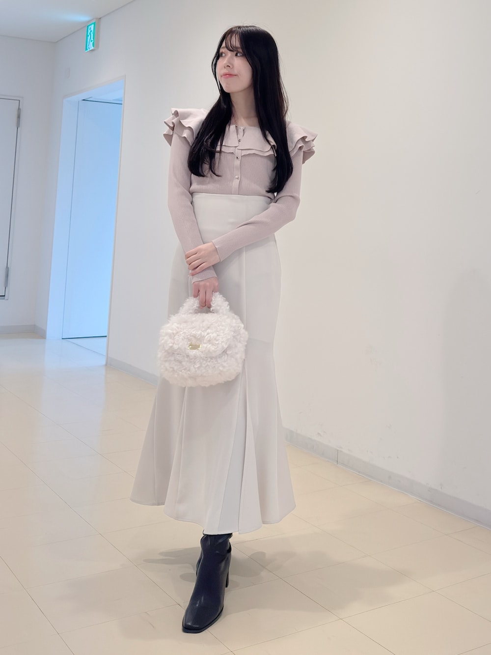 ベージュ系のニット/セーター、ホワイト系のスカート、ホワイト系のハンドバッグを着用したレディースの冬コーディネートの2枚目の写真