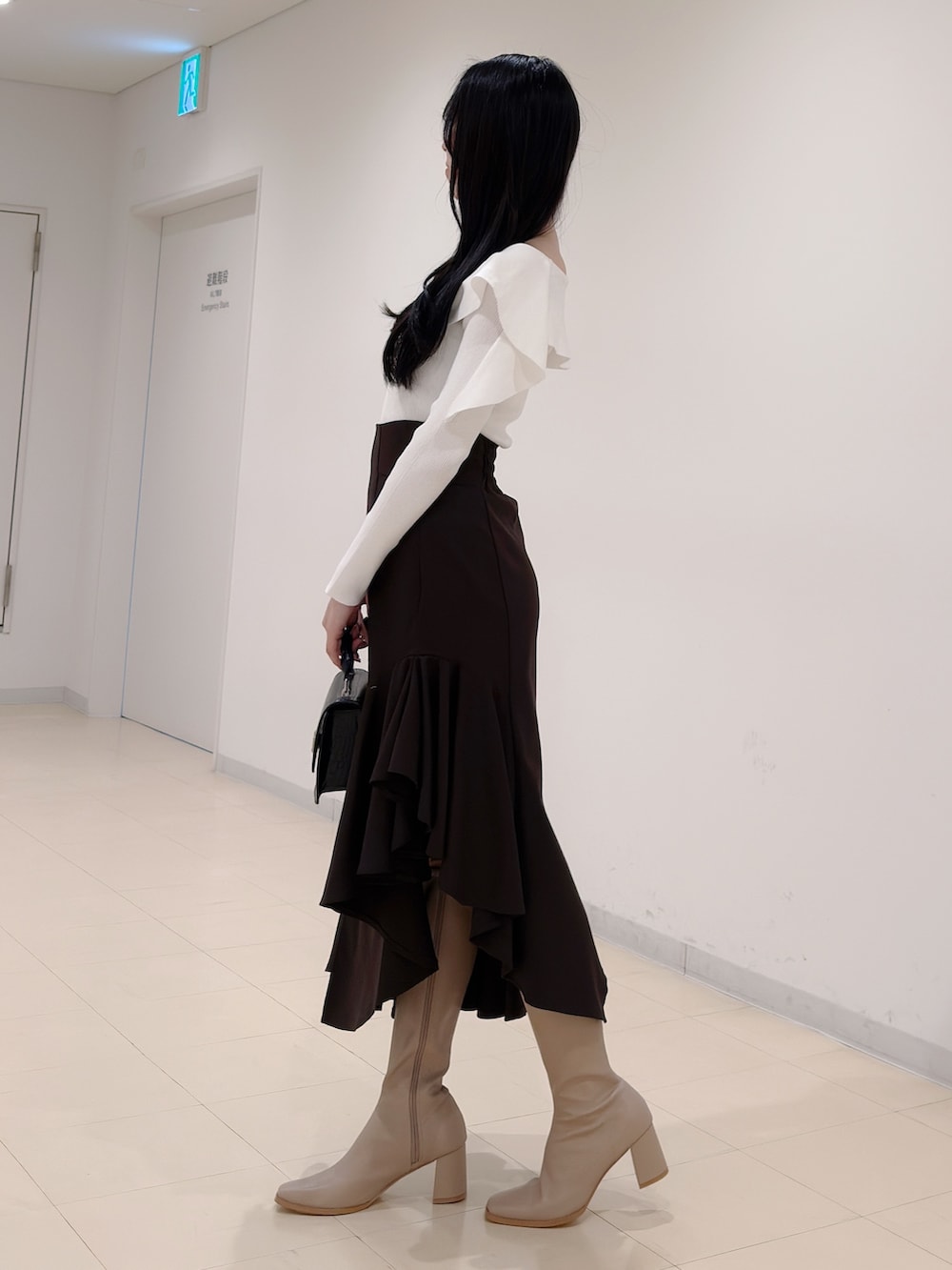 ホワイト系のニット/セーター、ブラウン系のスカート、ブラック系のハンドバッグを着用したレディースの秋コーディネートの4枚目の写真