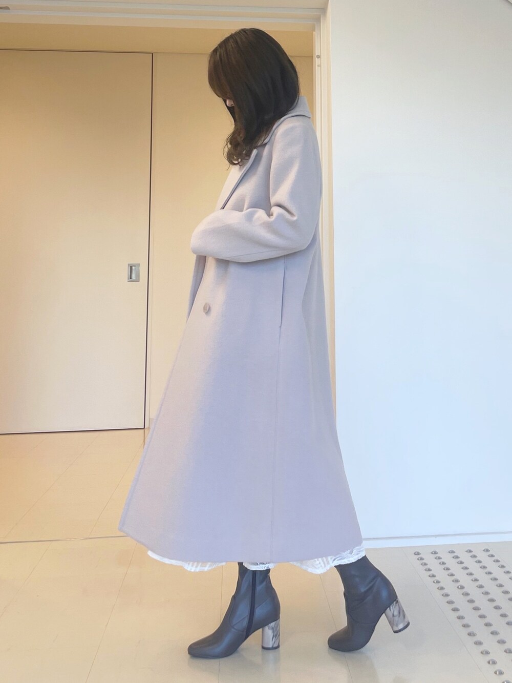 グレー系のニット/セーター、ホワイト系のスカート、ベージュ系のチェスターコートを着用したレディースの秋コーディネートの6枚目の写真