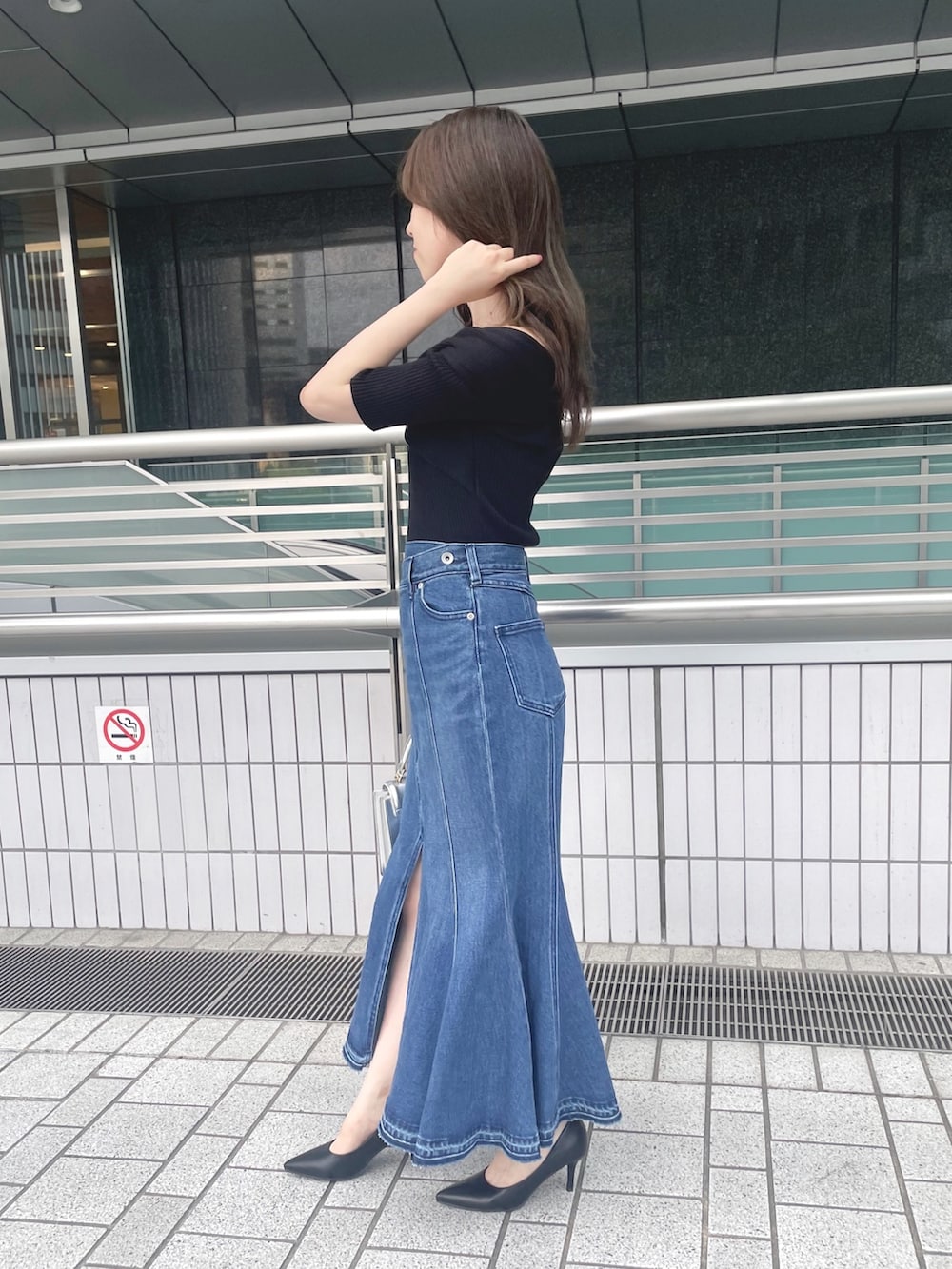 ブラック系のニット/セーター、ブルー系のデニムスカート、シルバー系のハンドバッグを着用したレディースの夏コーディネートの4枚目の写真