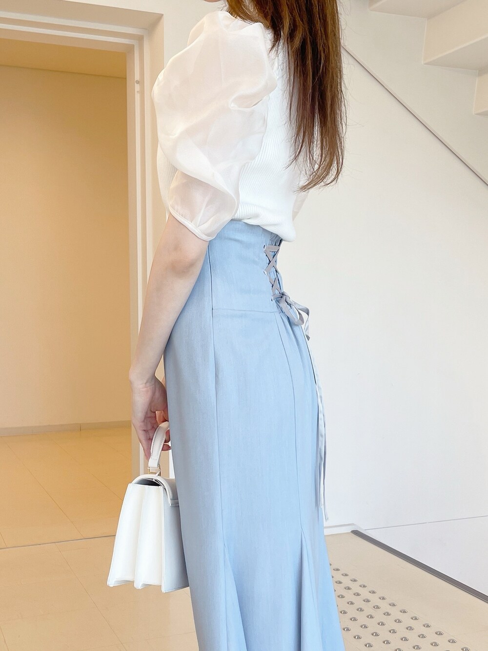 ホワイト系のニット/セーター、ブルー系のスカート、ホワイト系のハンドバッグを着用したレディースの夏コーディネートの5枚目の写真