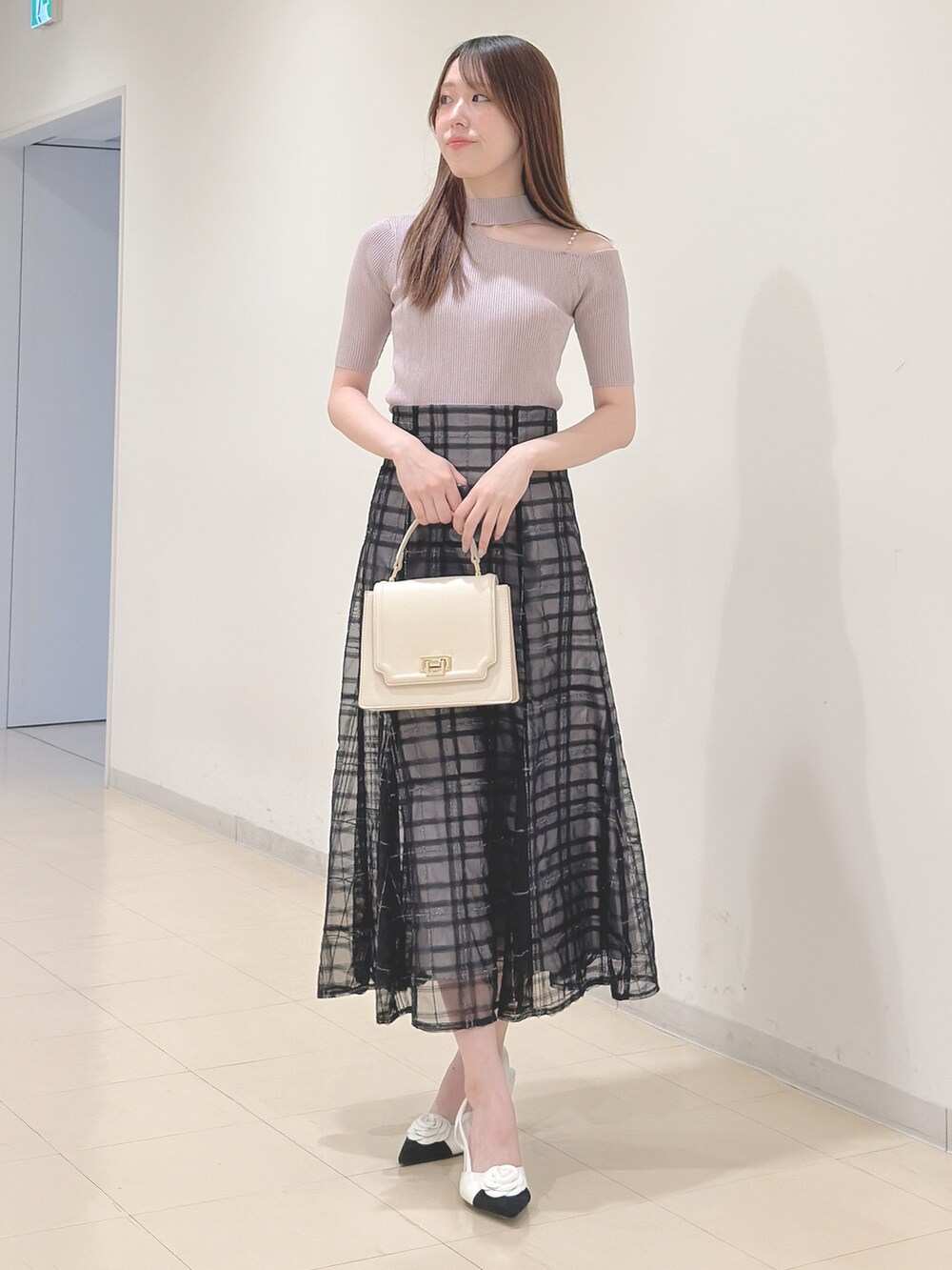 ベージュ系のニット/セーター、ブルー系のスカート、ホワイト系のハンドバッグを着用したレディースの春コーディネートの3枚目の写真