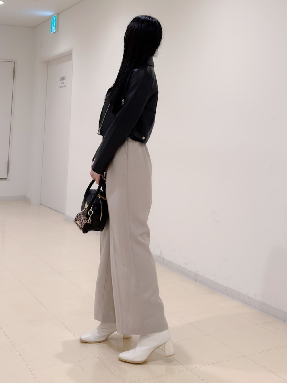 ブラック系のライダースジャケット、ベージュ系のつなぎ/オールインワン、ブラック系のハンドバッグを着用したレディースの秋コーディネートの3枚目の写真