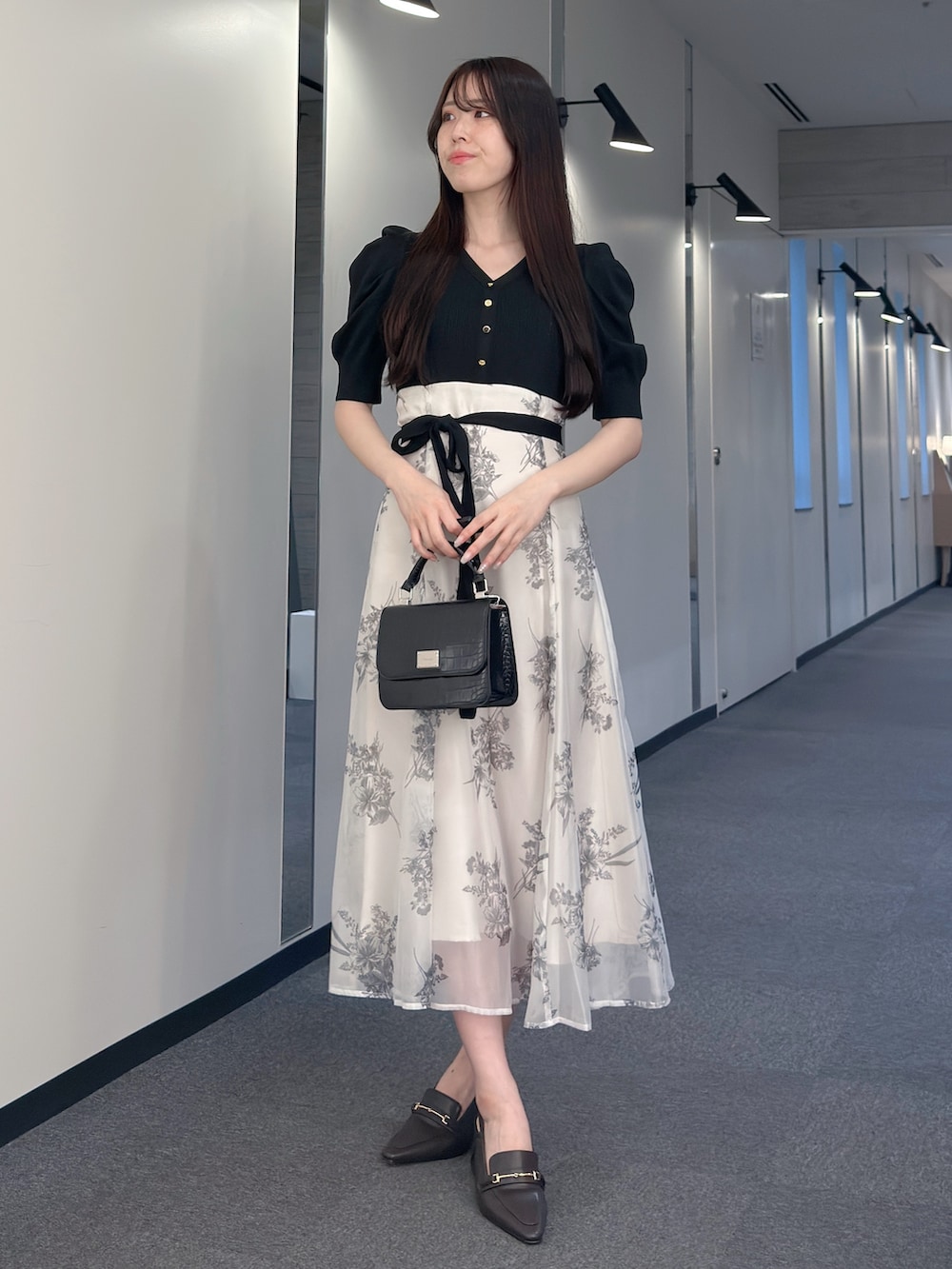 ブラック系のワンピース、ブラック系のハンドバッグ、ブラウン系のパンプスを着用したレディースの春コーディネートの2枚目の写真