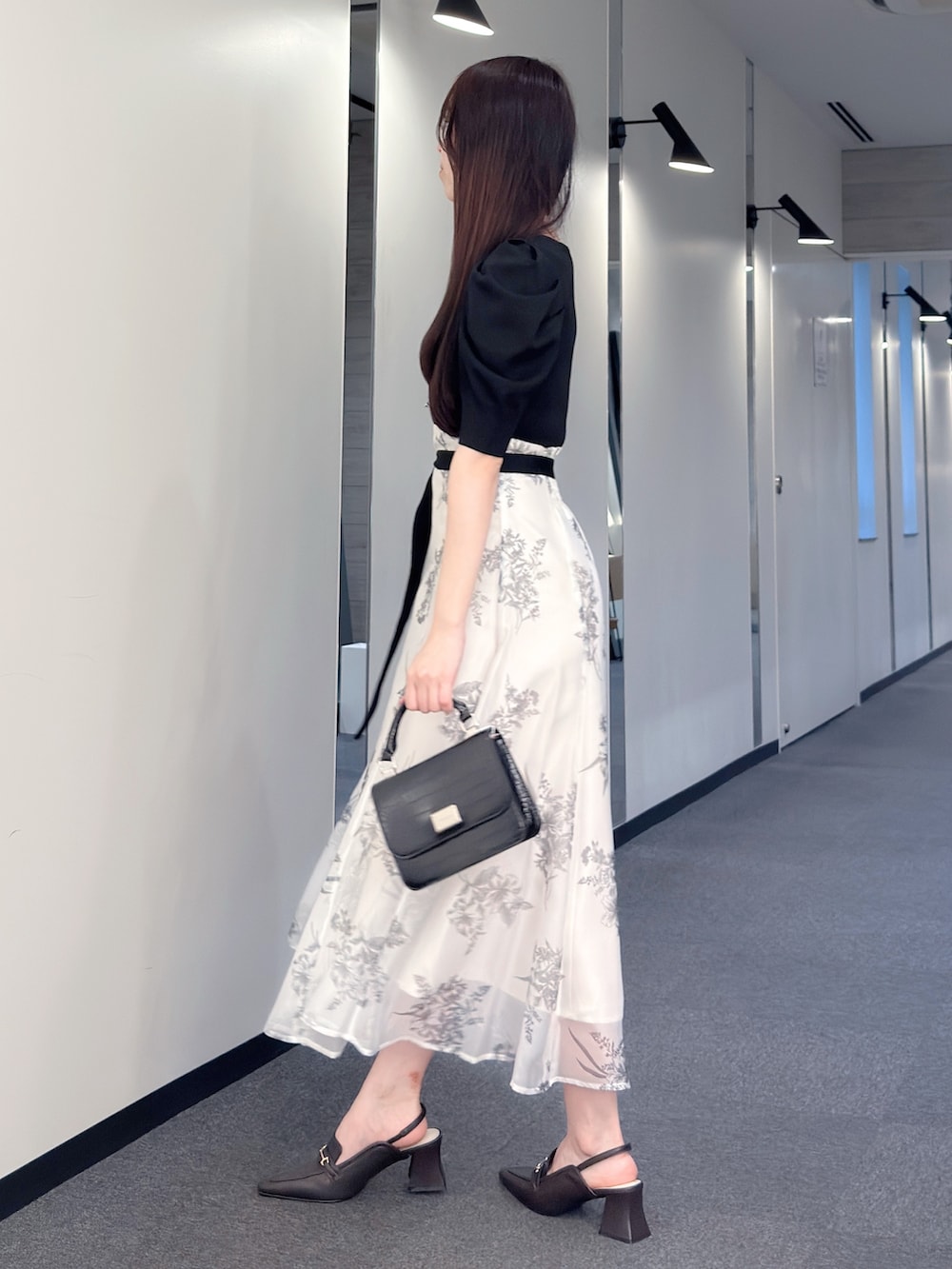 ブラック系のワンピース、ブラック系のハンドバッグ、ブラウン系のパンプスを着用したレディースの春コーディネートの3枚目の写真