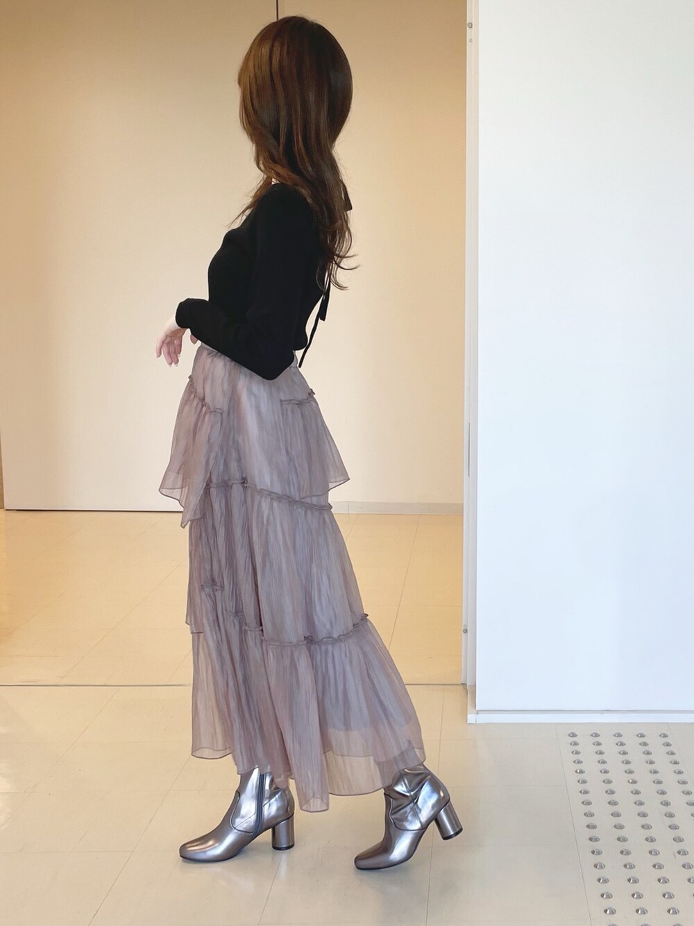 ゴールド系のブーツ、ブラウン系のスカート、ブラック系のニット/セーターを着用したレディースの冬コーディネートの4枚目の写真