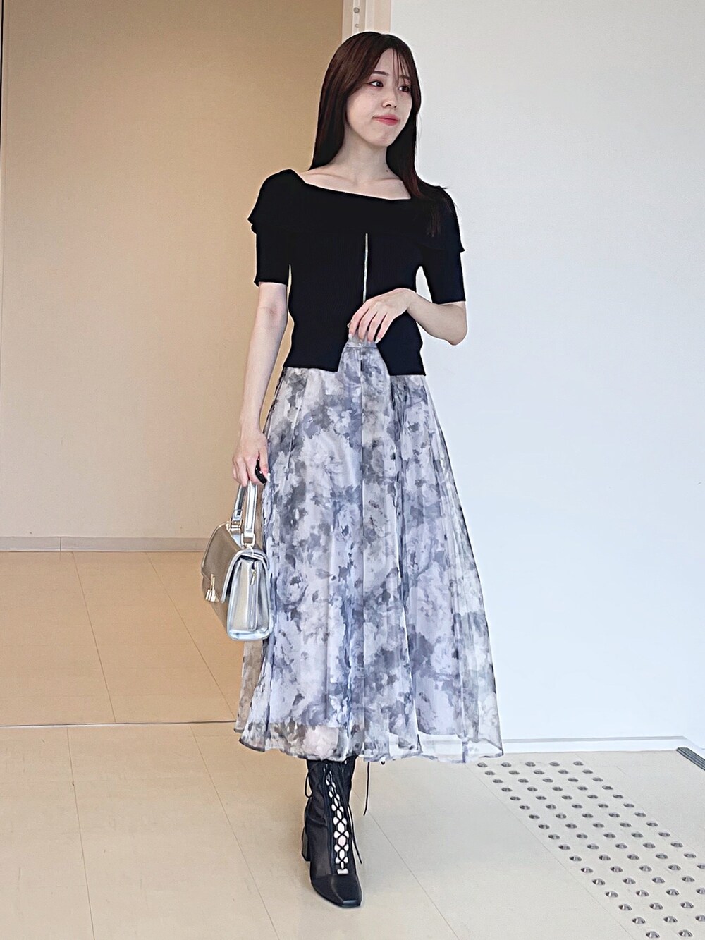 ブラック系のニット/セーター、グレー系のスカート、シルバー系のハンドバッグを着用したレディースの夏コーディネートの3枚目の写真