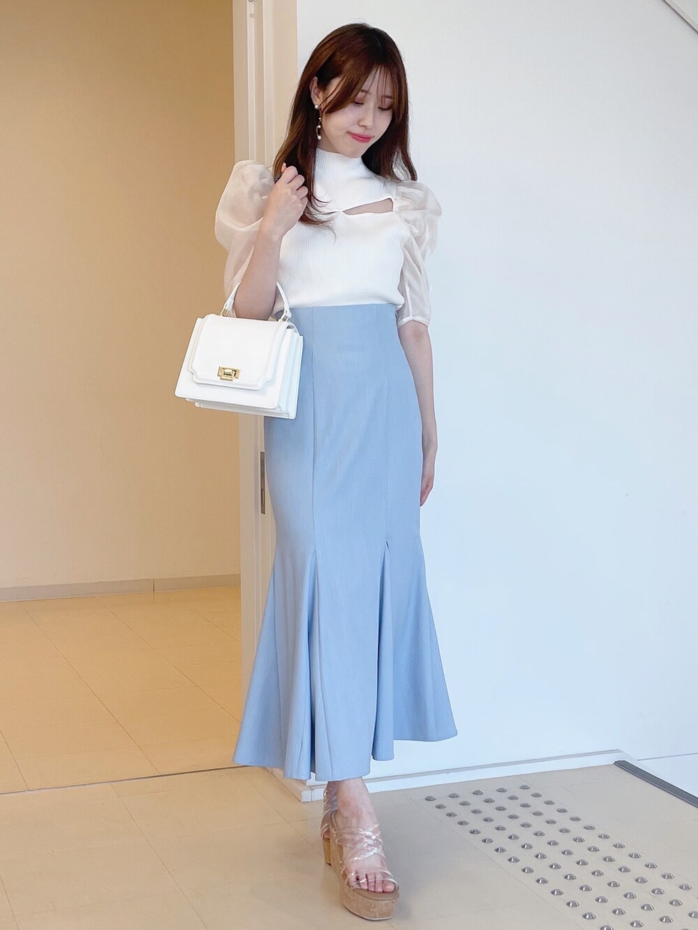 ホワイト系のニット/セーター、ブルー系のスカート、ホワイト系のハンドバッグを着用したレディースの夏コーディネートの2枚目の写真