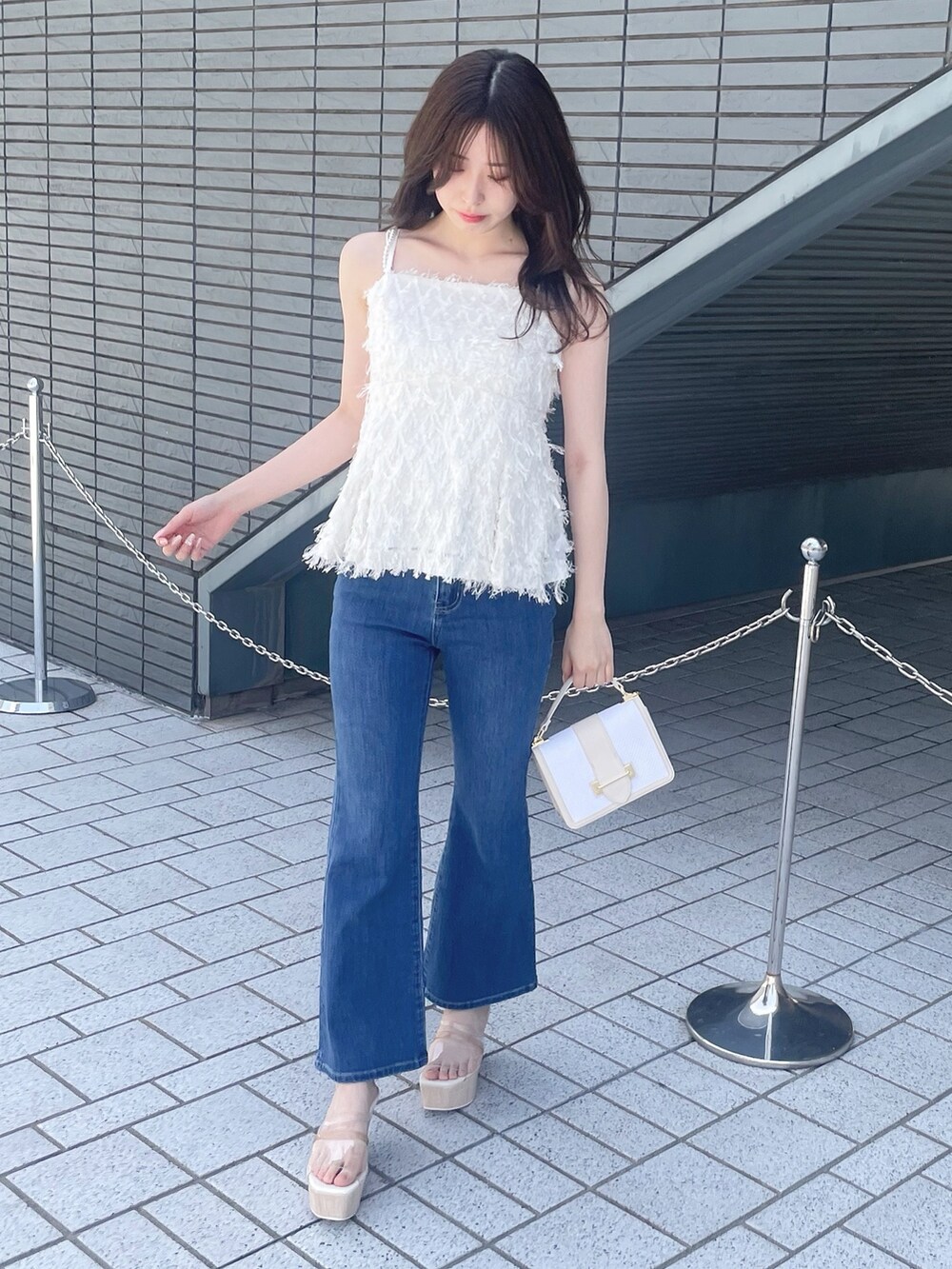 ホワイト系のキャミソール、ブルー系のデニムパンツ、その他のサンダルを着用したレディースの春コーディネートの2枚目の写真