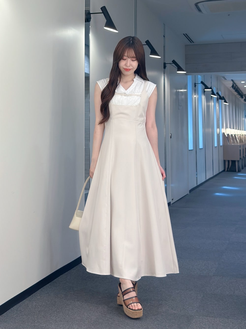 ピンク系のワンピース、ホワイト系のハンドバッグ、ブラウン系のサンダルを着用したレディースの夏コーディネートの2枚目の写真