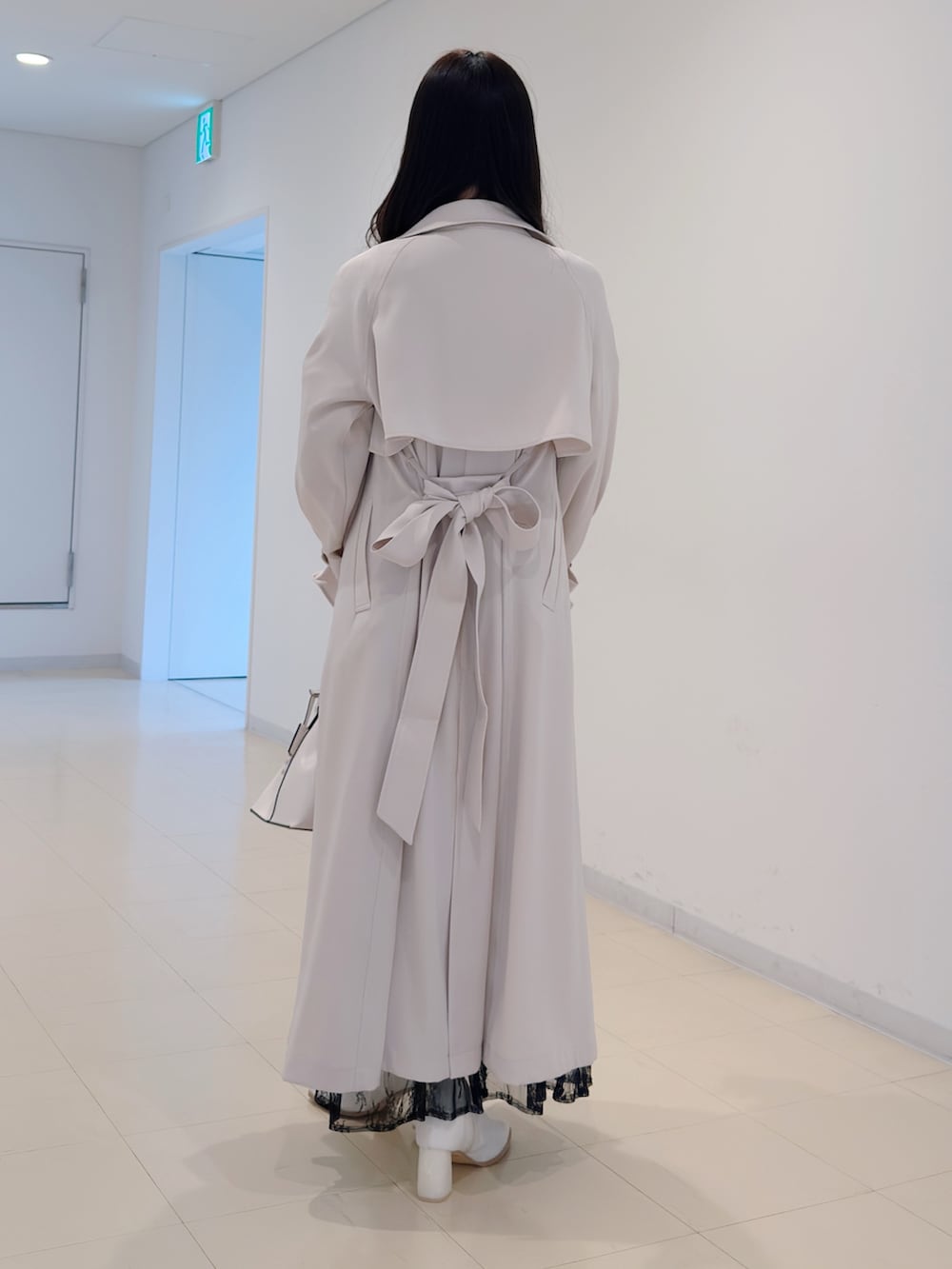 ホワイト系のトレンチコート、ブルー系のワンピース、ホワイト系のブーツを着用したレディースの冬コーディネートの4枚目の写真