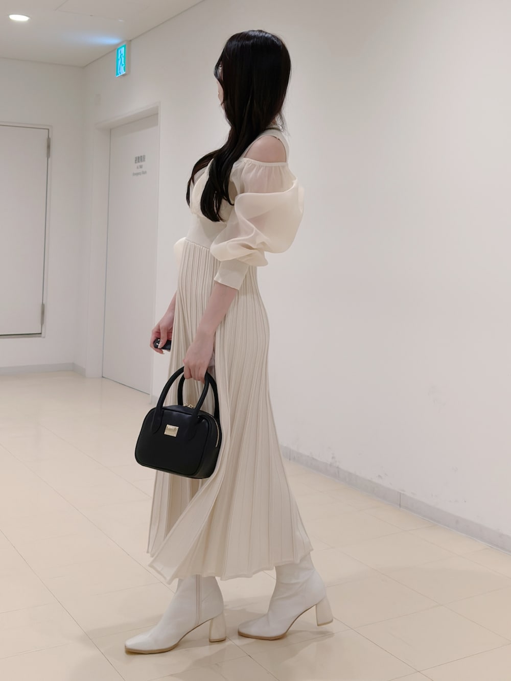 ホワイト系のワンピース、ブラック系のハンドバッグ、ホワイト系のブーツを着用したレディースの冬コーディネートの3枚目の写真