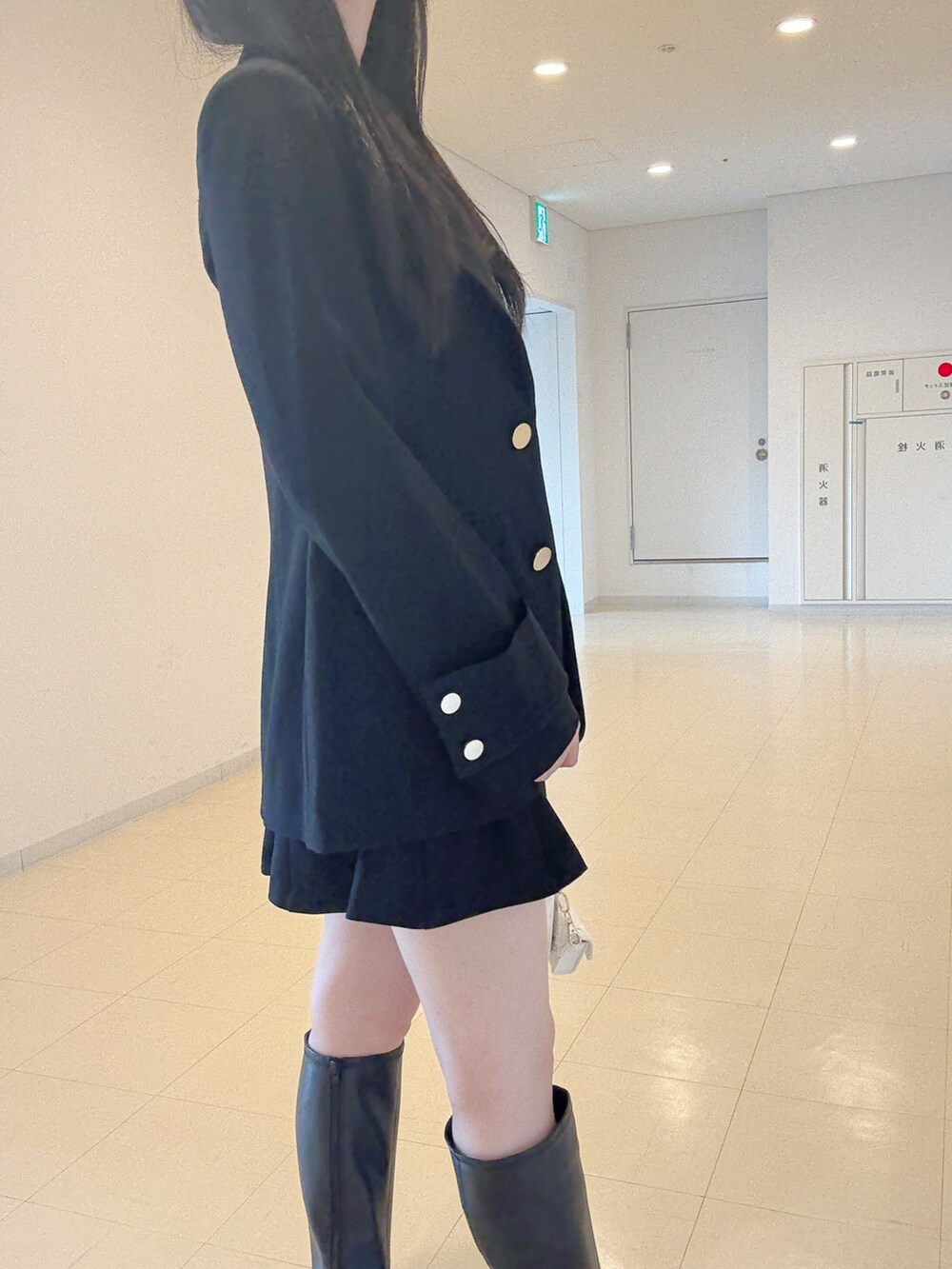 ブラック系のテーラードジャケット、グレー系のニット/セーター、ブラック系のスカートを着用したレディースの秋コーディネートの7枚目の写真