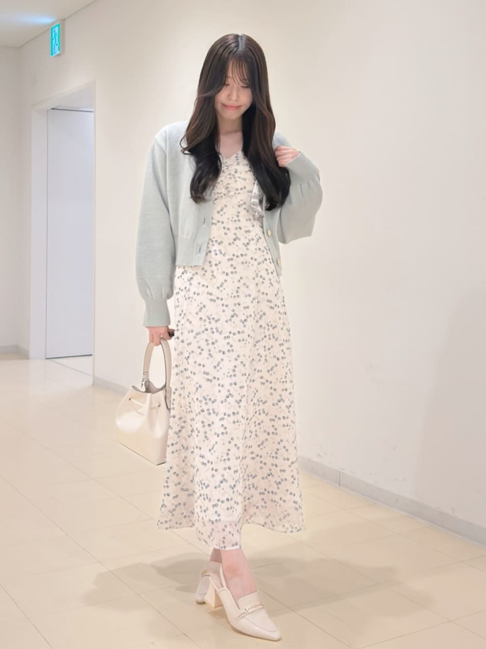 ホワイト系のショルダーバッグ、グリーン系のカーディガン/ボレロ、ホワイト系のワンピースを着用したレディースの冬コーディネートの2枚目の写真