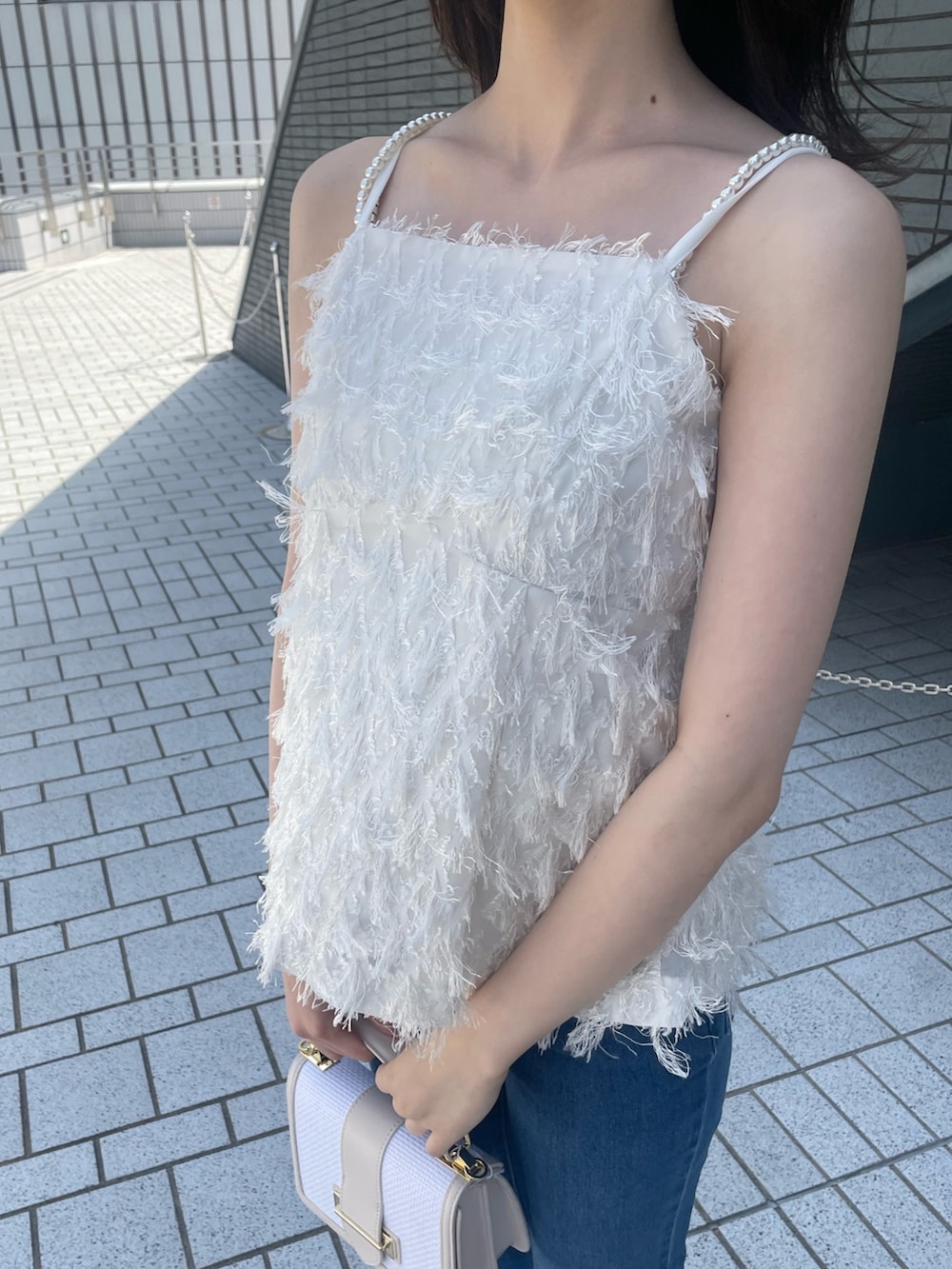 ホワイト系のキャミソール、ブルー系のデニムパンツ、その他のサンダルを着用したレディースの春コーディネートの7枚目の写真