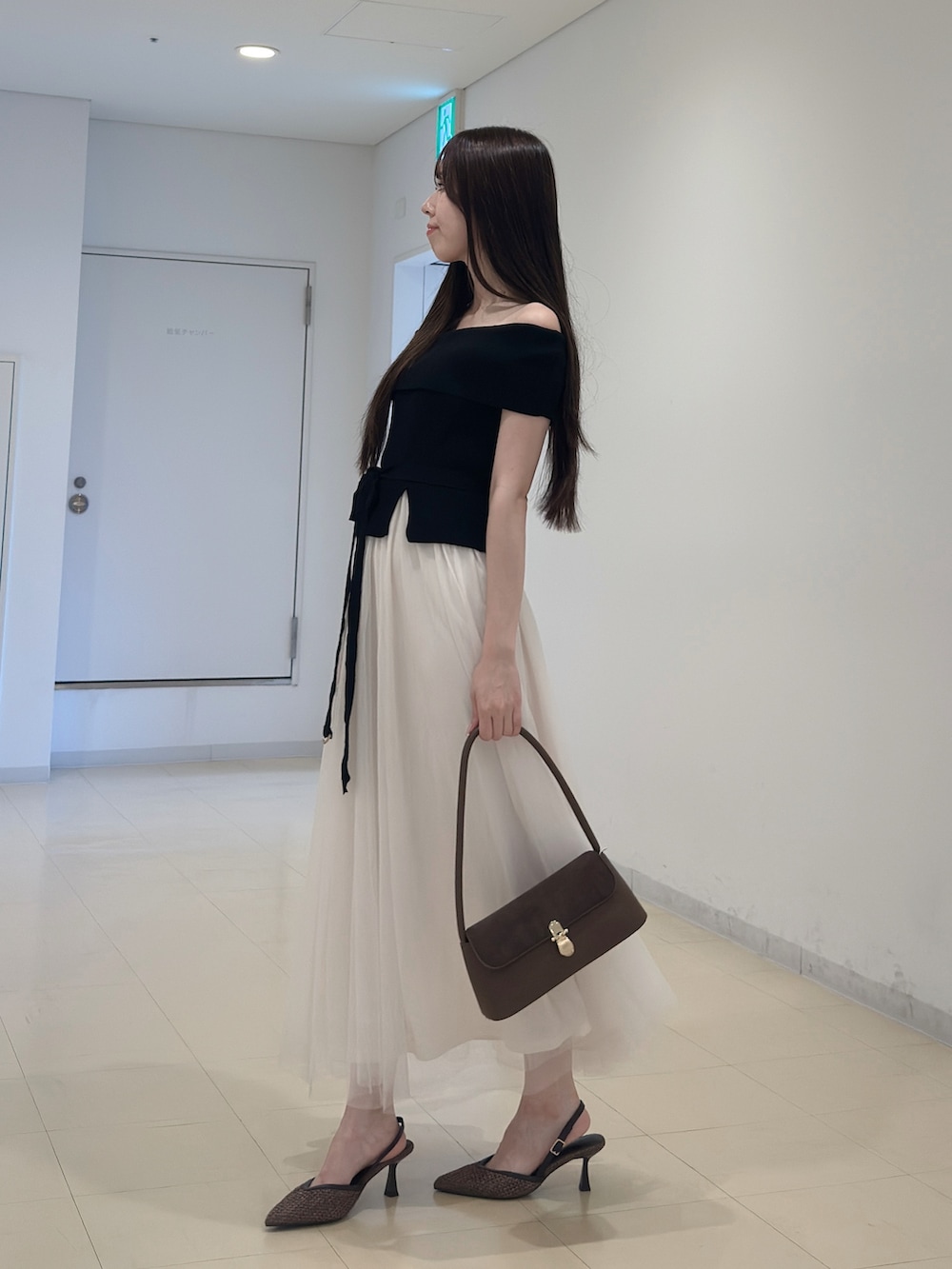 ブラック系のワンピース、ブラウン系のハンドバッグ、ブラウン系のパンプスを着用したレディースの夏コーディネートの3枚目の写真