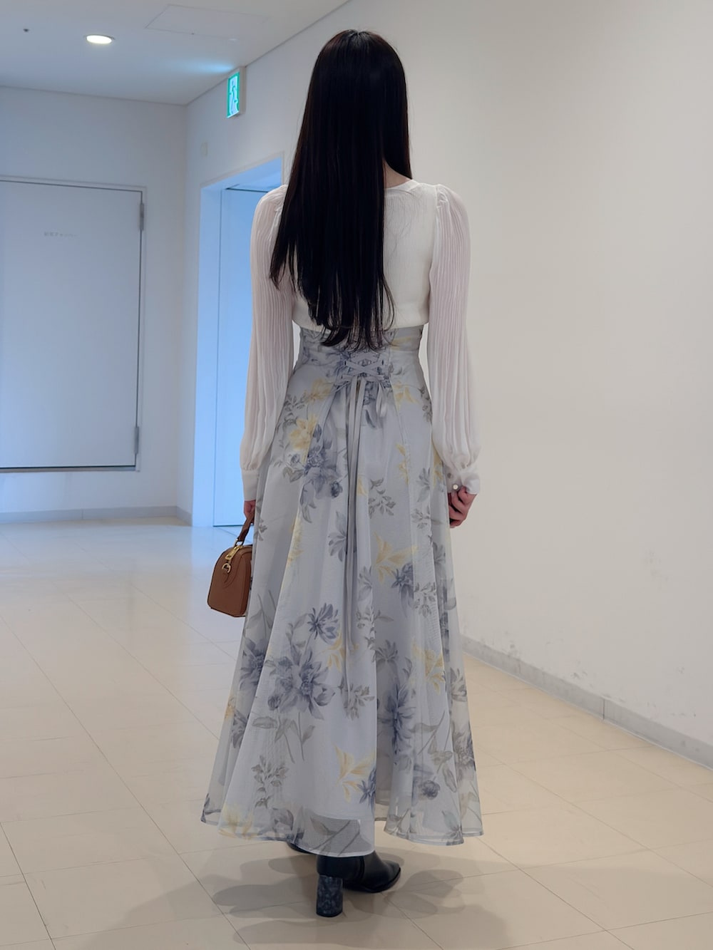 ホワイト系のニット/セーター、グリーン系のスカート、ブラウン系のハンドバッグを着用したレディースの冬コーディネートの4枚目の写真