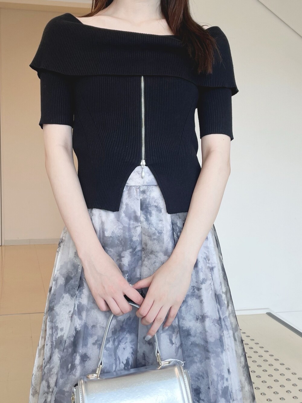 ブラック系のニット/セーター、グレー系のスカート、シルバー系のハンドバッグを着用したレディースの夏コーディネートの7枚目の写真