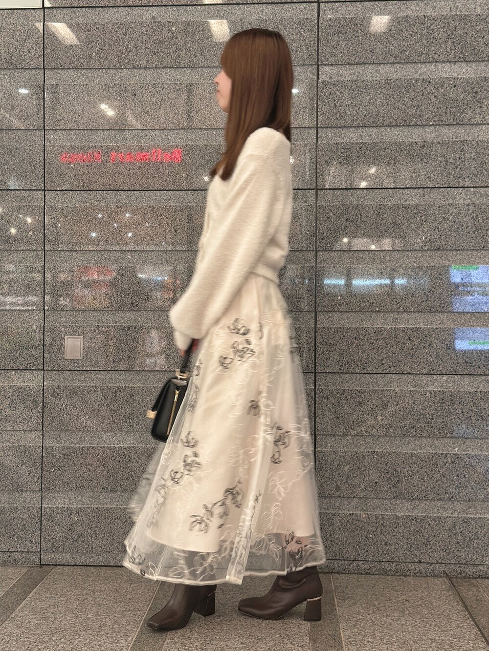 ホワイト系のカーディガン/ボレロ、ホワイト系のスカート、ブラック系のハンドバッグを着用したレディースの秋コーディネートの4枚目の写真