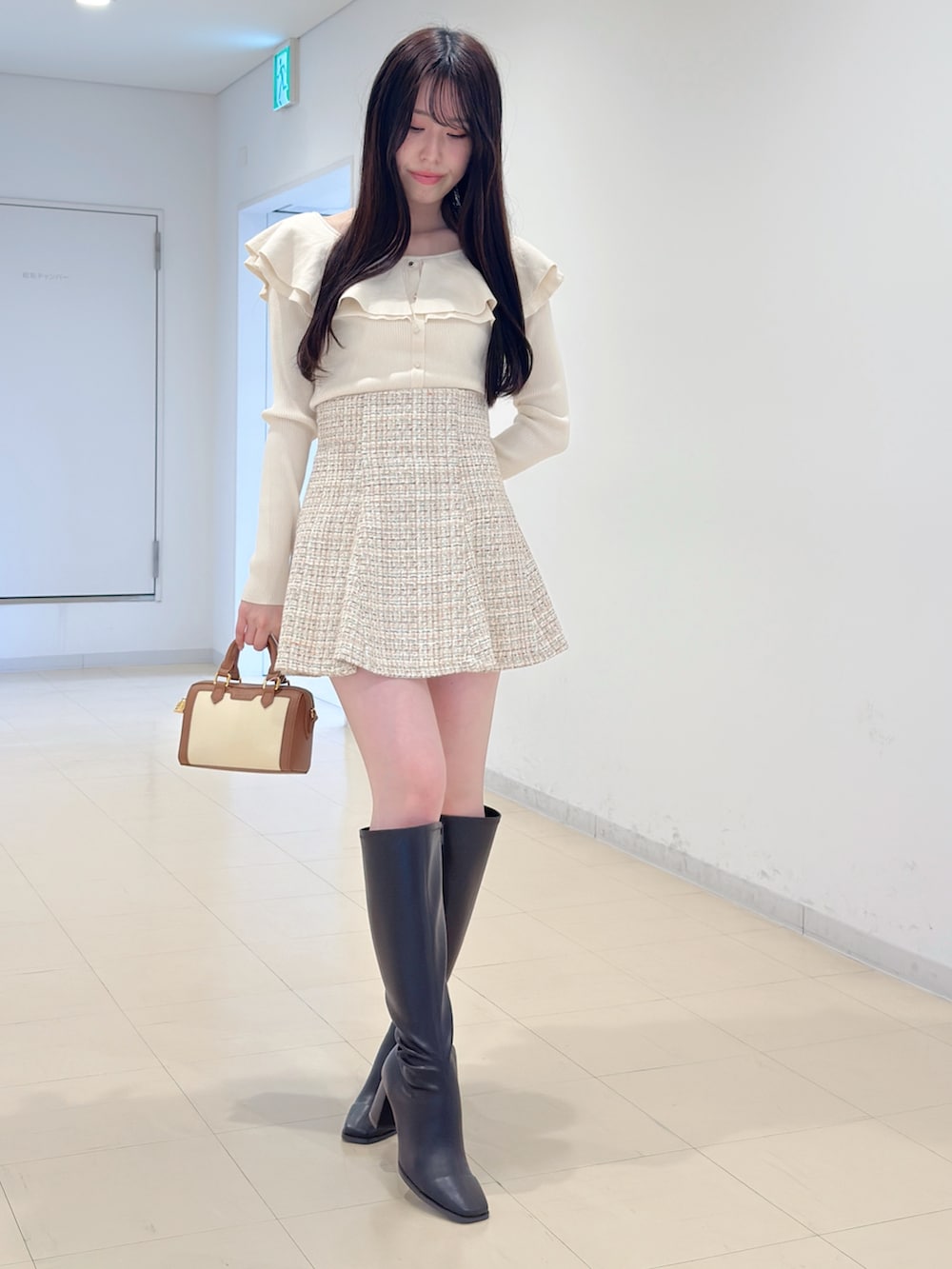 ホワイト系のニット/セーター、ベージュ系のスカート、ブラウン系のハンドバッグを着用したレディースの冬コーディネートの2枚目の写真