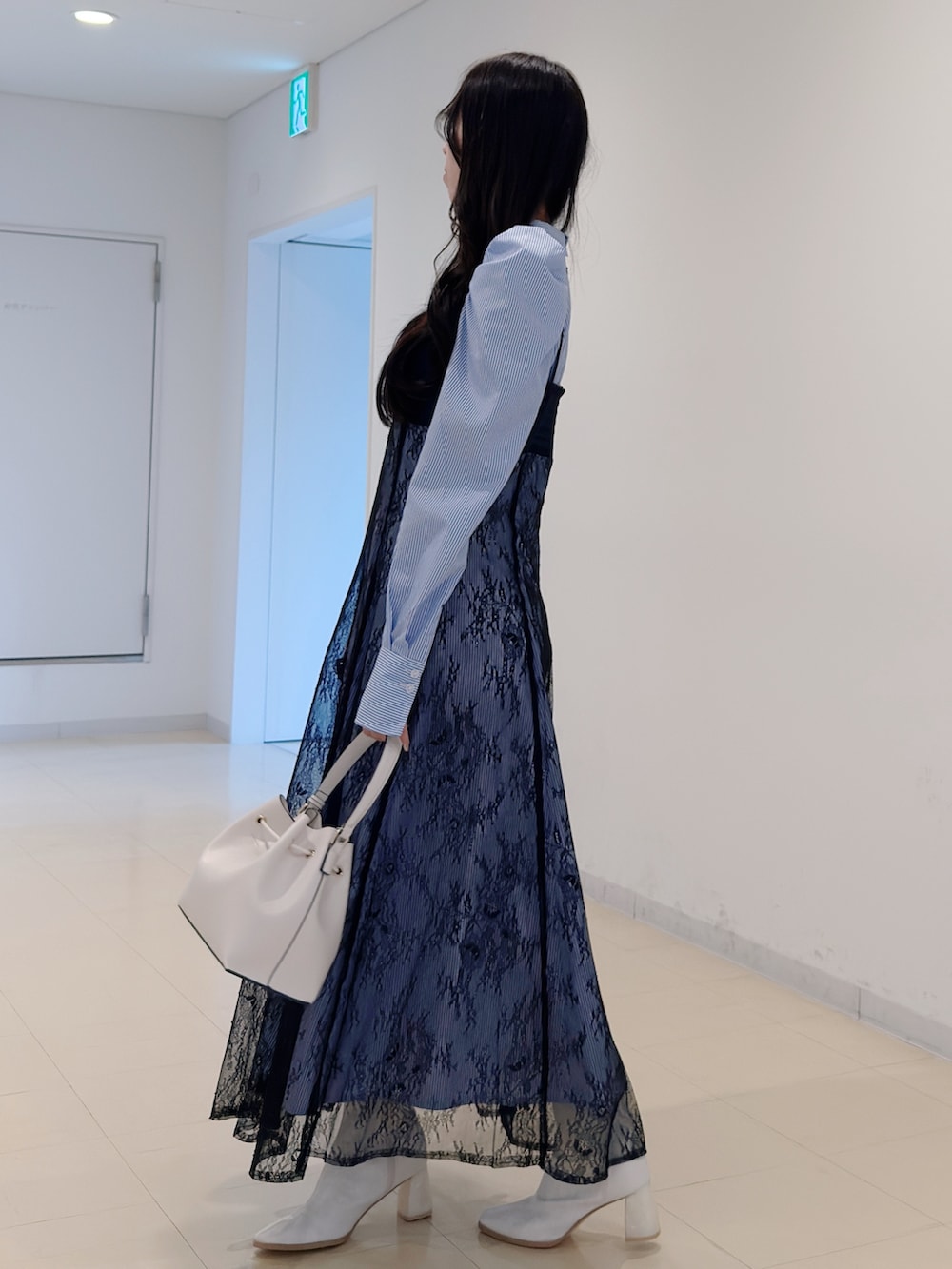 ブルー系のワンピース、ホワイト系のショルダーバッグ、ホワイト系のブーツを着用したレディースの冬コーディネートの3枚目の写真