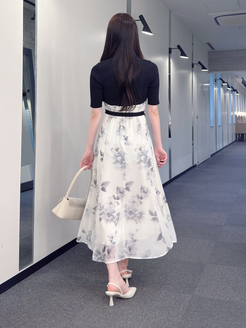 ブラック系のワンピース、ホワイト系のハンドバッグ、ホワイト系のパンプスを着用したレディースの春コーディネートの3枚目の写真