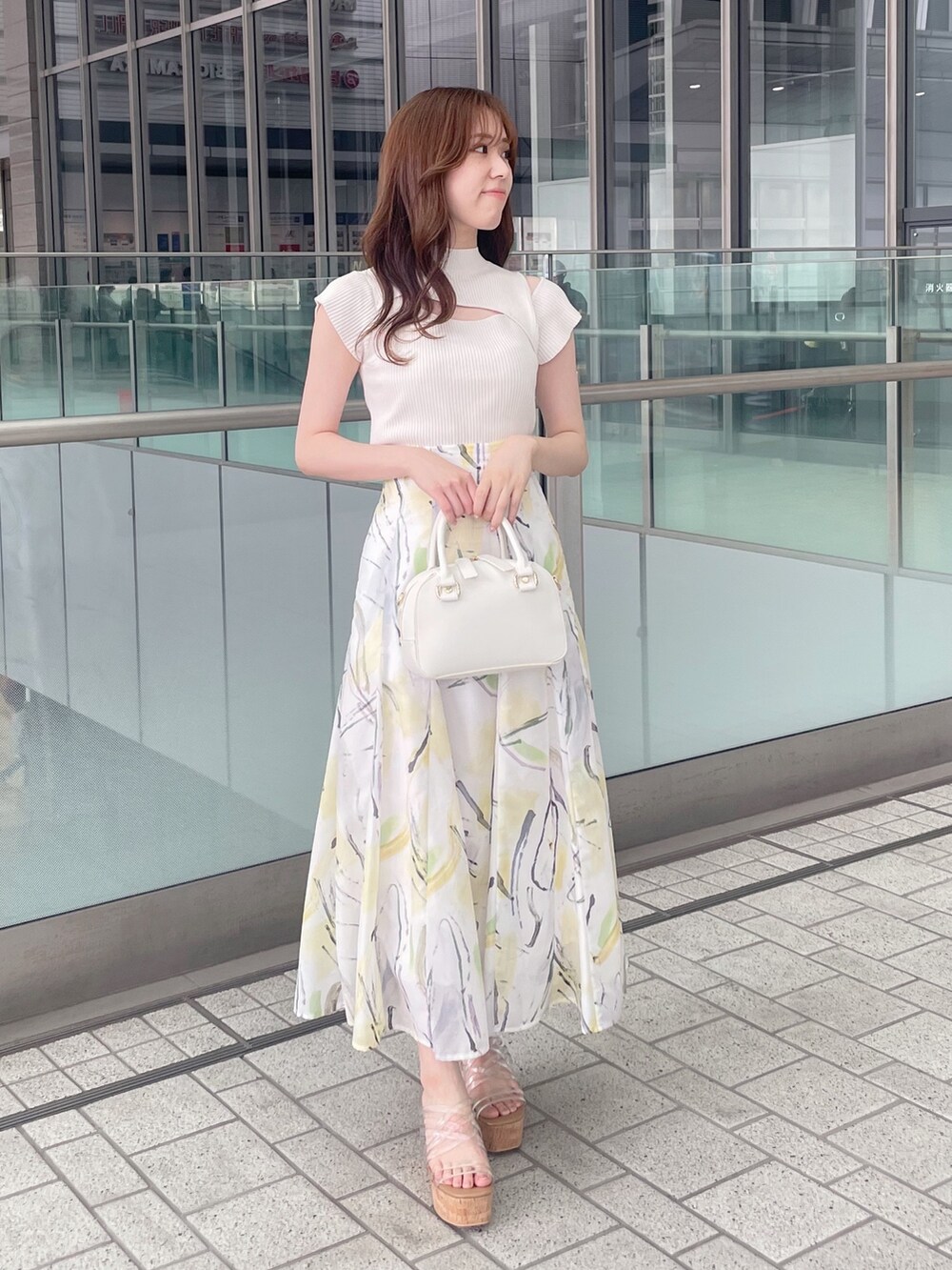 ホワイト系のニット/セーター、イエロー系のスカート、ホワイト系のボストンバッグを着用したレディースの夏コーディネートの2枚目の写真