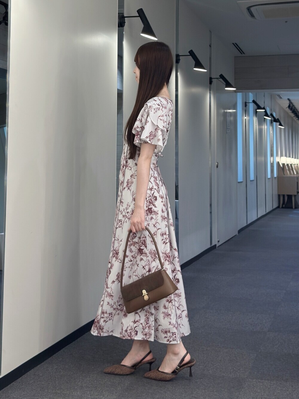 ブラウン系のハンドバッグ、ブラウン系のパンプス、レッド系のワンピースを着用したレディースの夏コーディネートの3枚目の写真