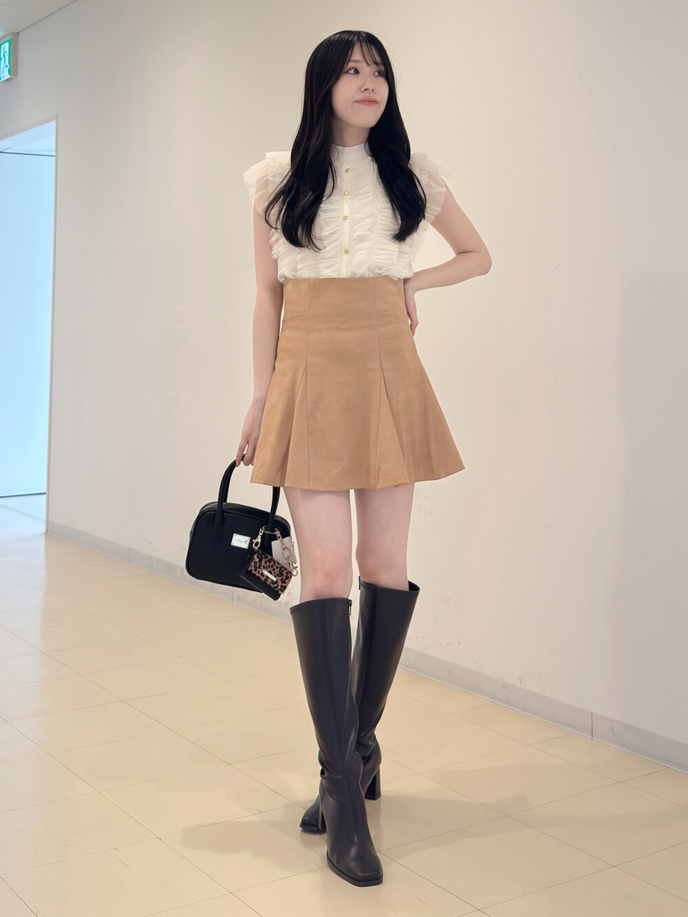 ホワイト系のニット/セーター、ブラック系のハンドバッグ、イエロー系のスカートを着用したレディースの夏コーディネートの3枚目の写真