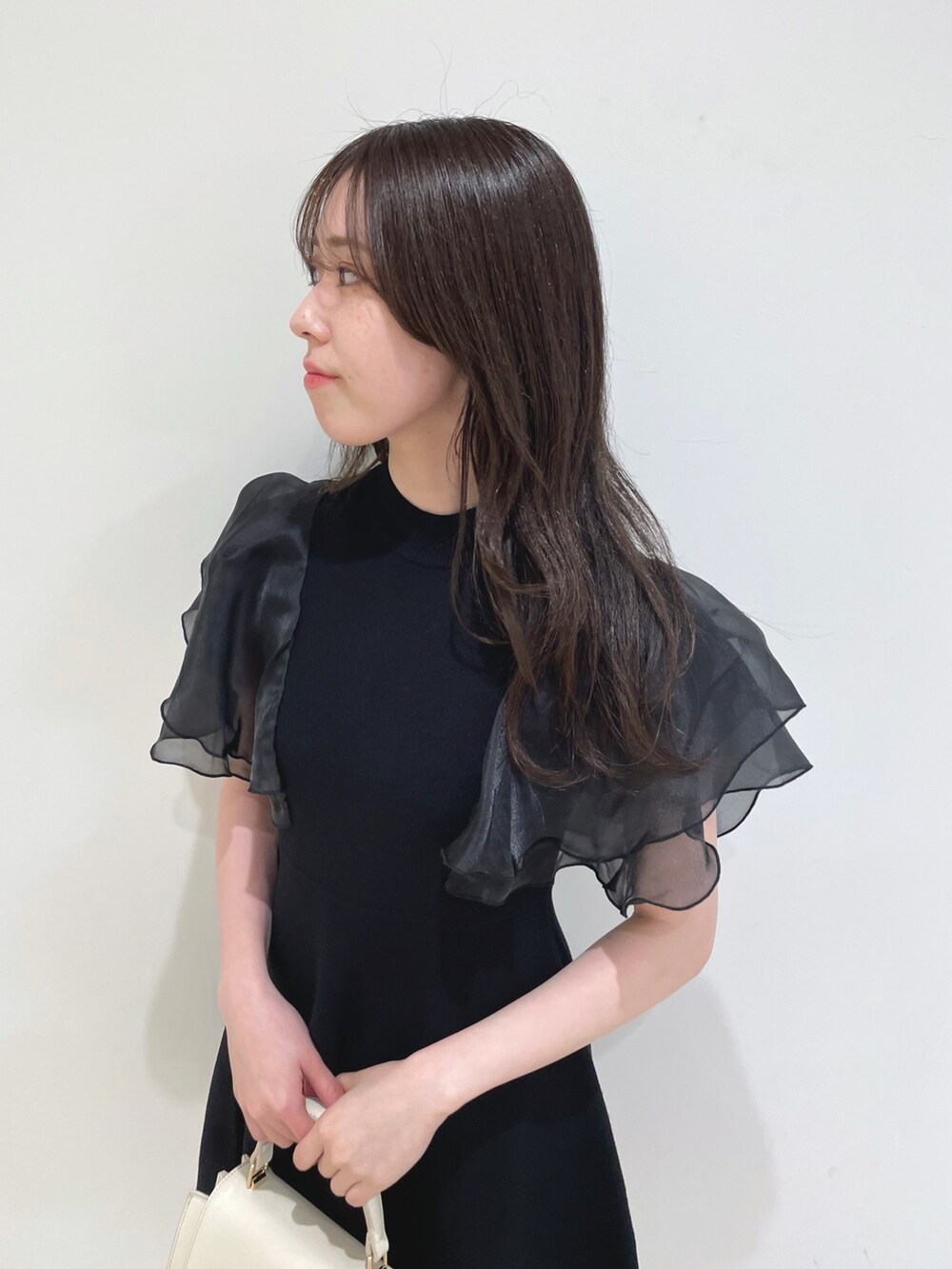 ブラック系のワンピース、ホワイト系のハンドバッグ、ホワイト系のブーツを着用したレディースの春コーディネートの7枚目の写真