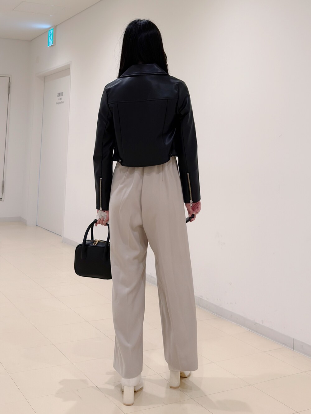 ブラック系のライダースジャケット、ベージュ系のつなぎ/オールインワン、ブラック系のハンドバッグを着用したレディースの秋コーディネートの4枚目の写真