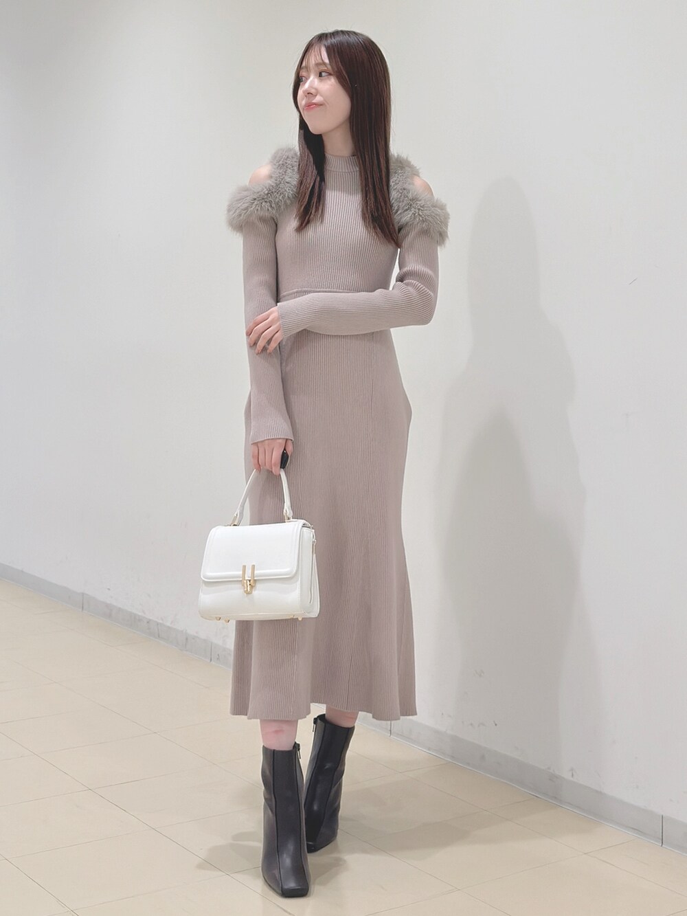 ベージュ系のワンピース、ホワイト系のハンドバッグ、ブラウン系のブーツを着用したレディースの冬コーディネートの3枚目の写真