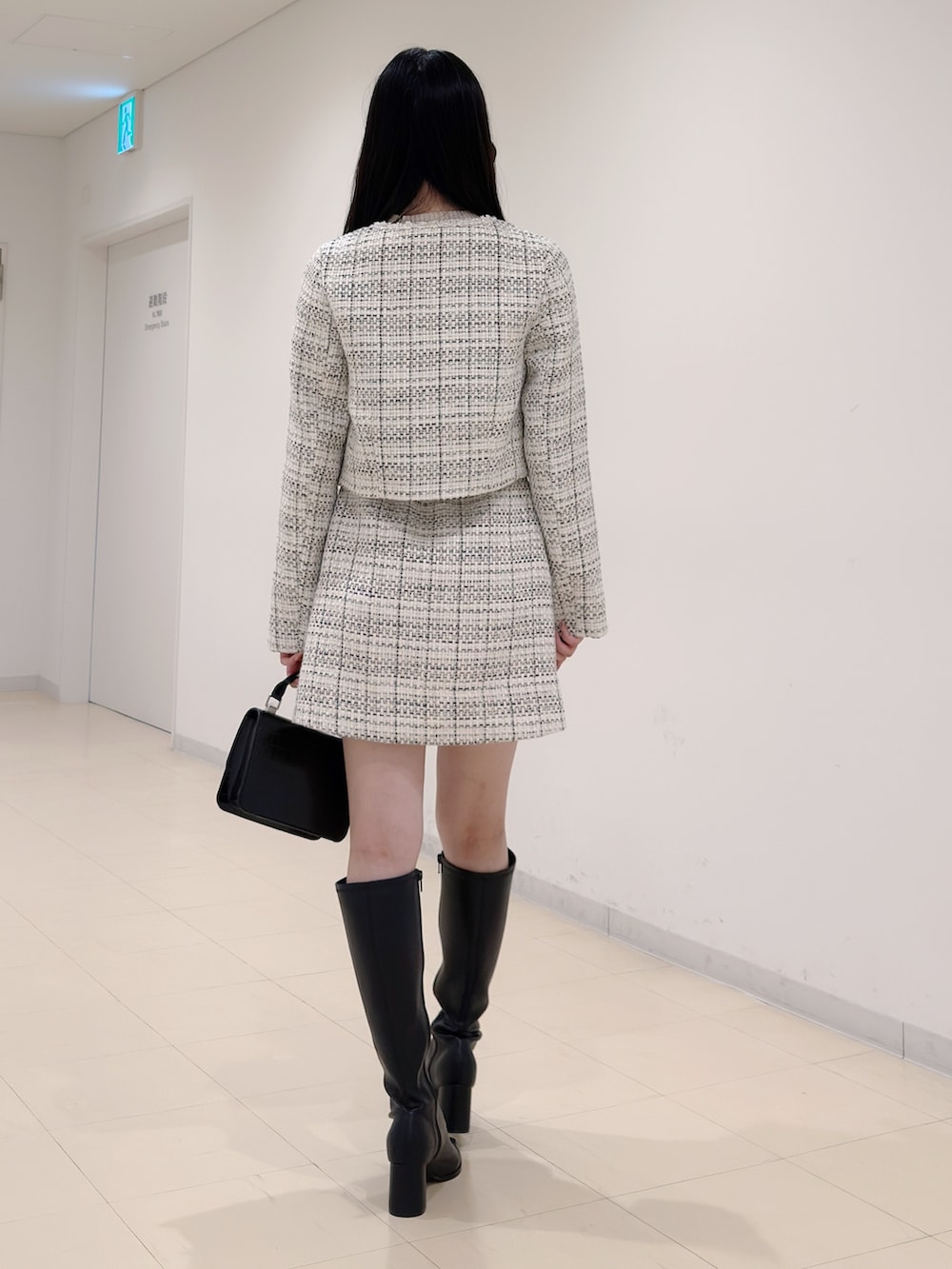 ホワイト系のノーカラージャケット、ベージュ系のニット/セーター、ホワイト系のスカートを着用したレディースの秋コーディネートの4枚目の写真