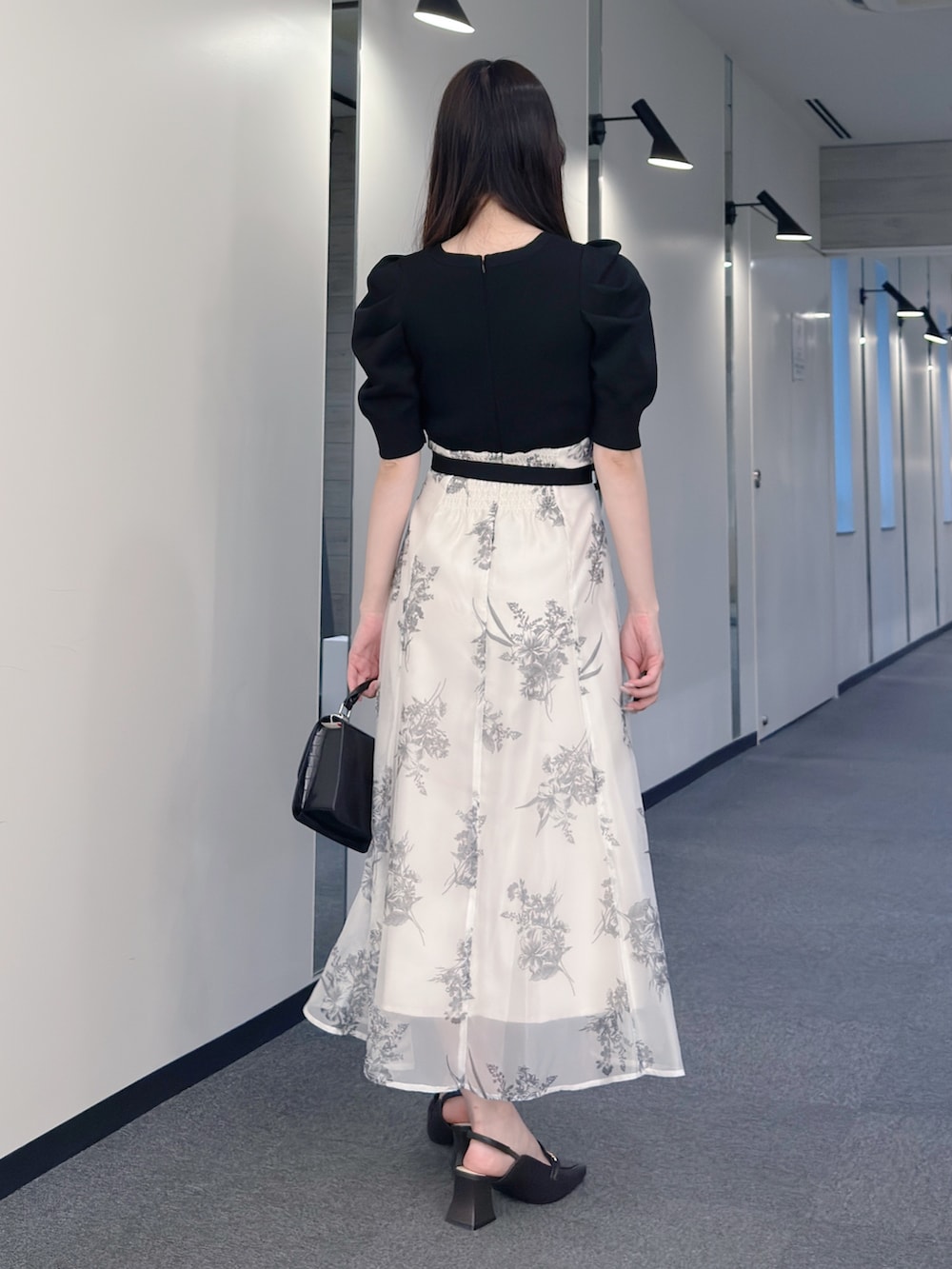 ブラック系のワンピース、ブラック系のハンドバッグ、ブラウン系のパンプスを着用したレディースの春コーディネートの4枚目の写真