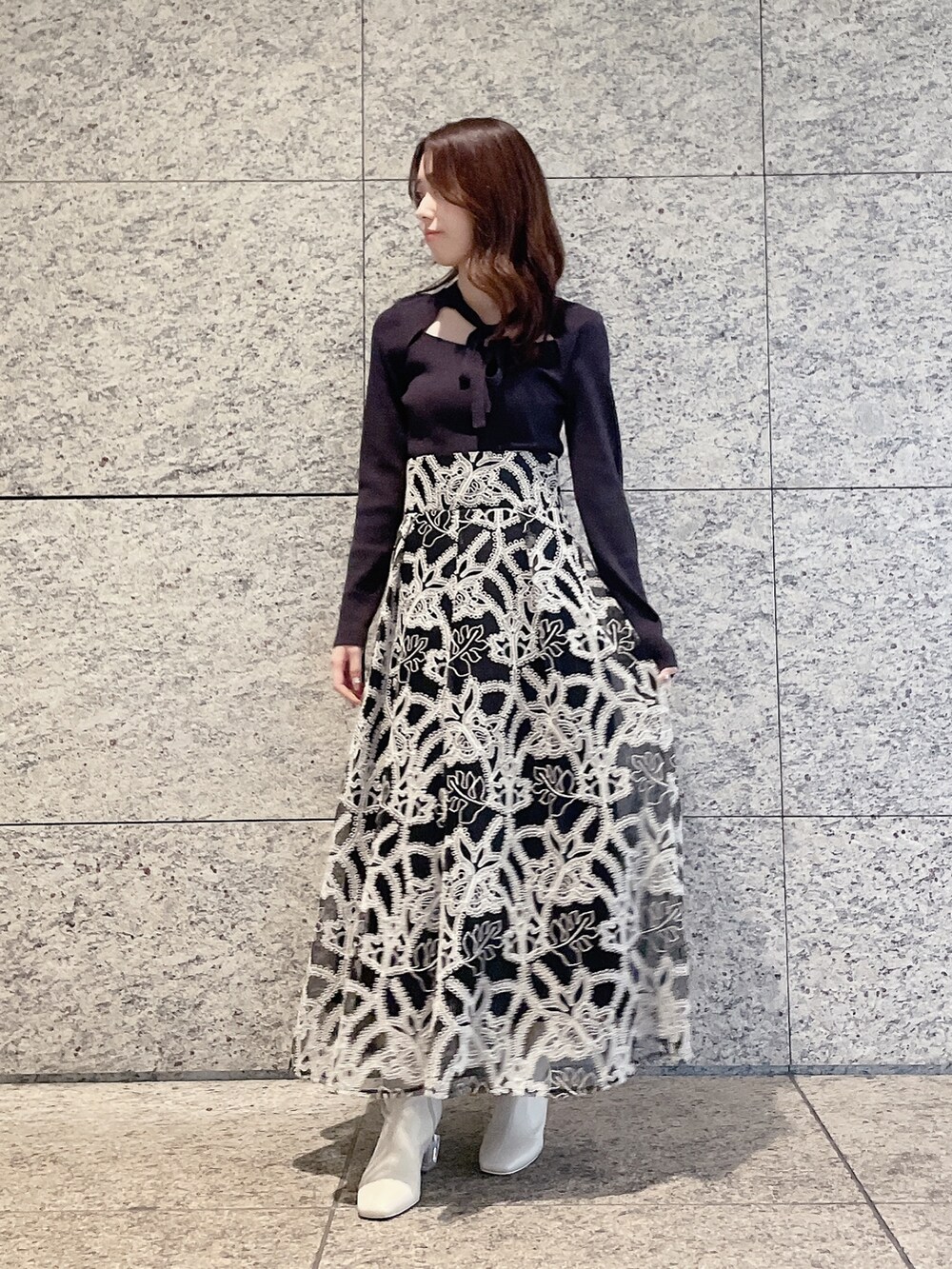 ブラウン系のニット/セーター、ブラック系のスカート、ホワイト系のブーツを着用したレディースの冬コーディネートの2枚目の写真